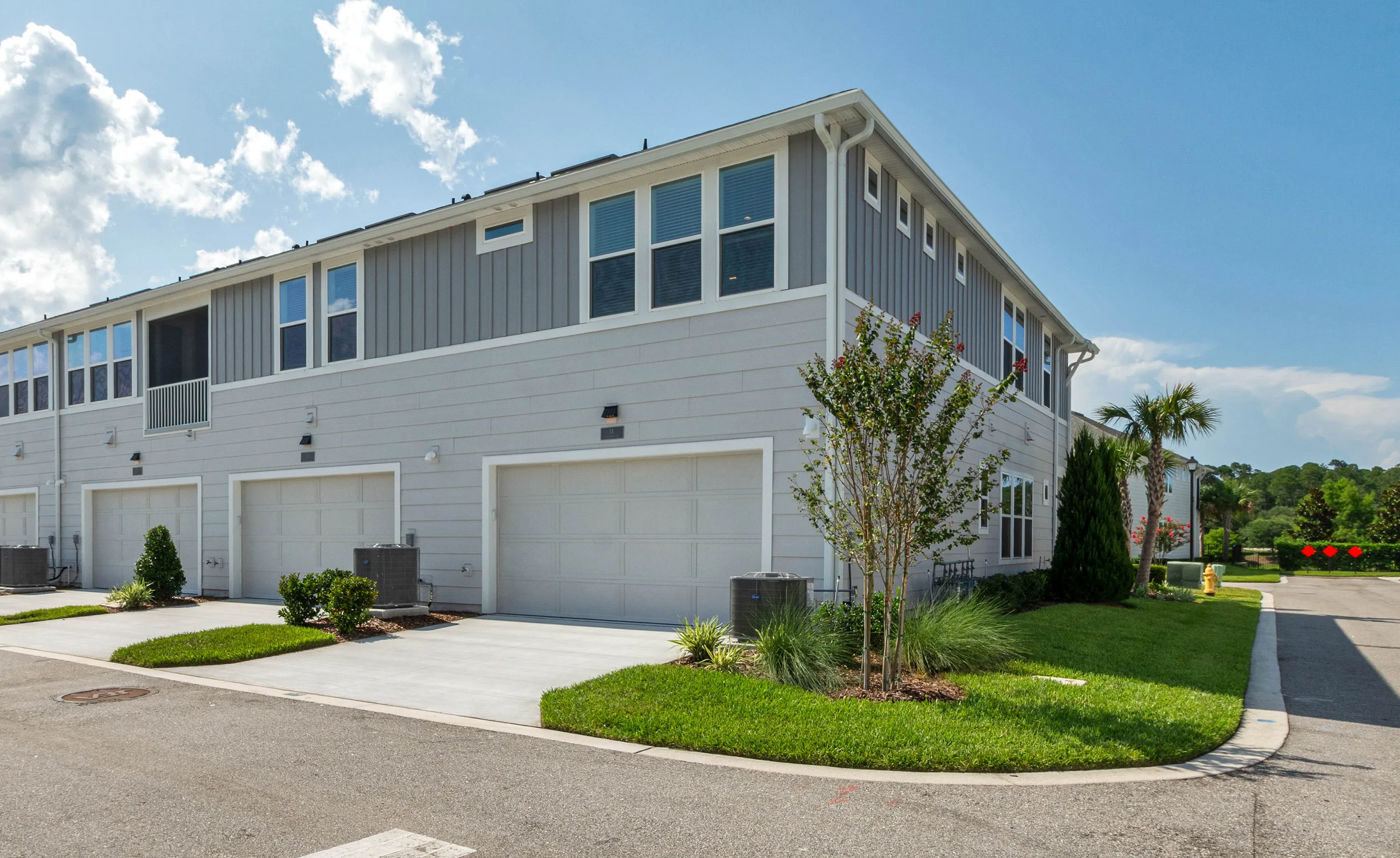 Exterior front view of the Bartram B plan in Nocatee, showing multi-unit grey siding townhomes with attached garages.