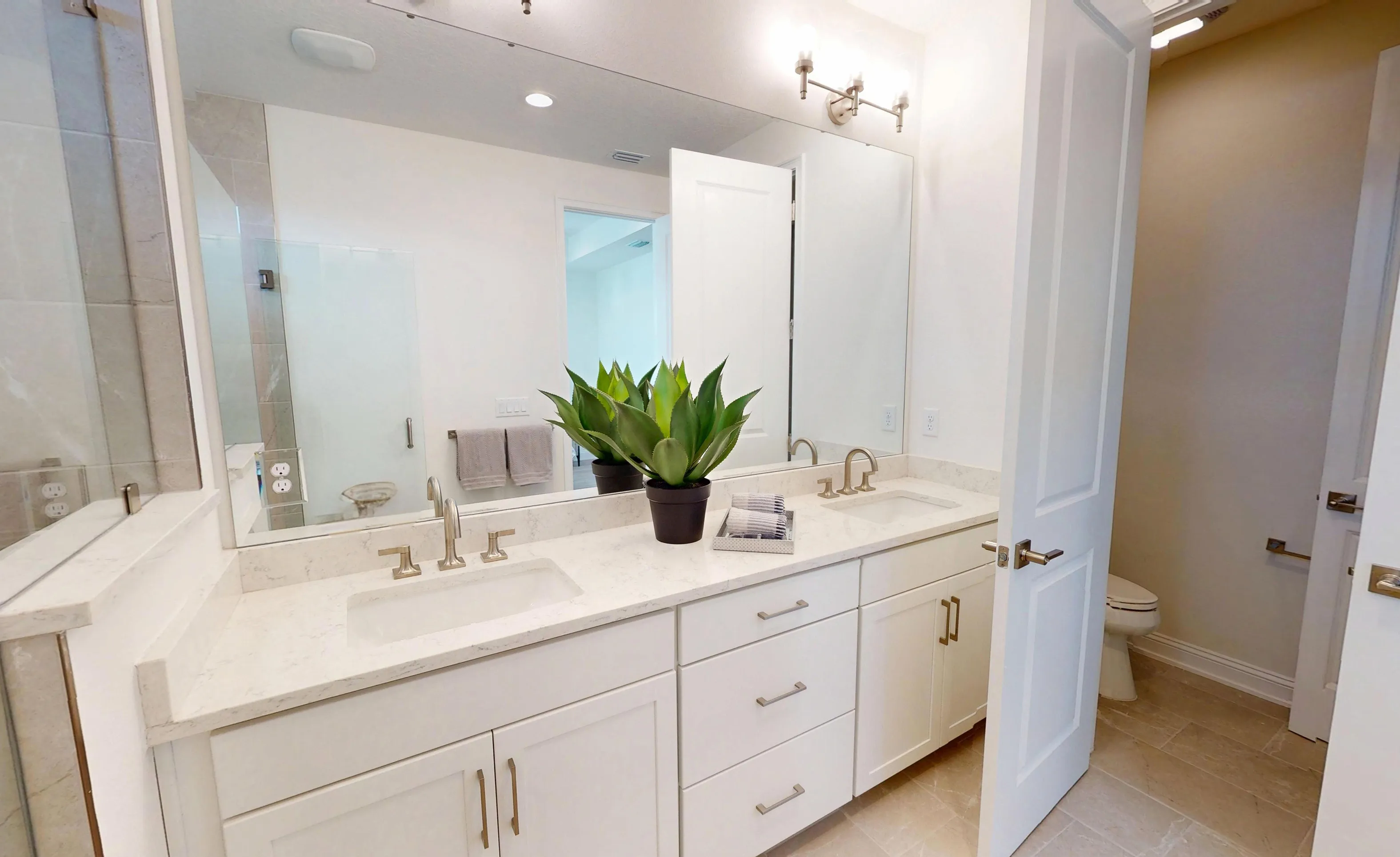 Primary bathroom in the Bartram floor plan featuring dual-sink vanity with white cabinets, light countertops, and mirror.