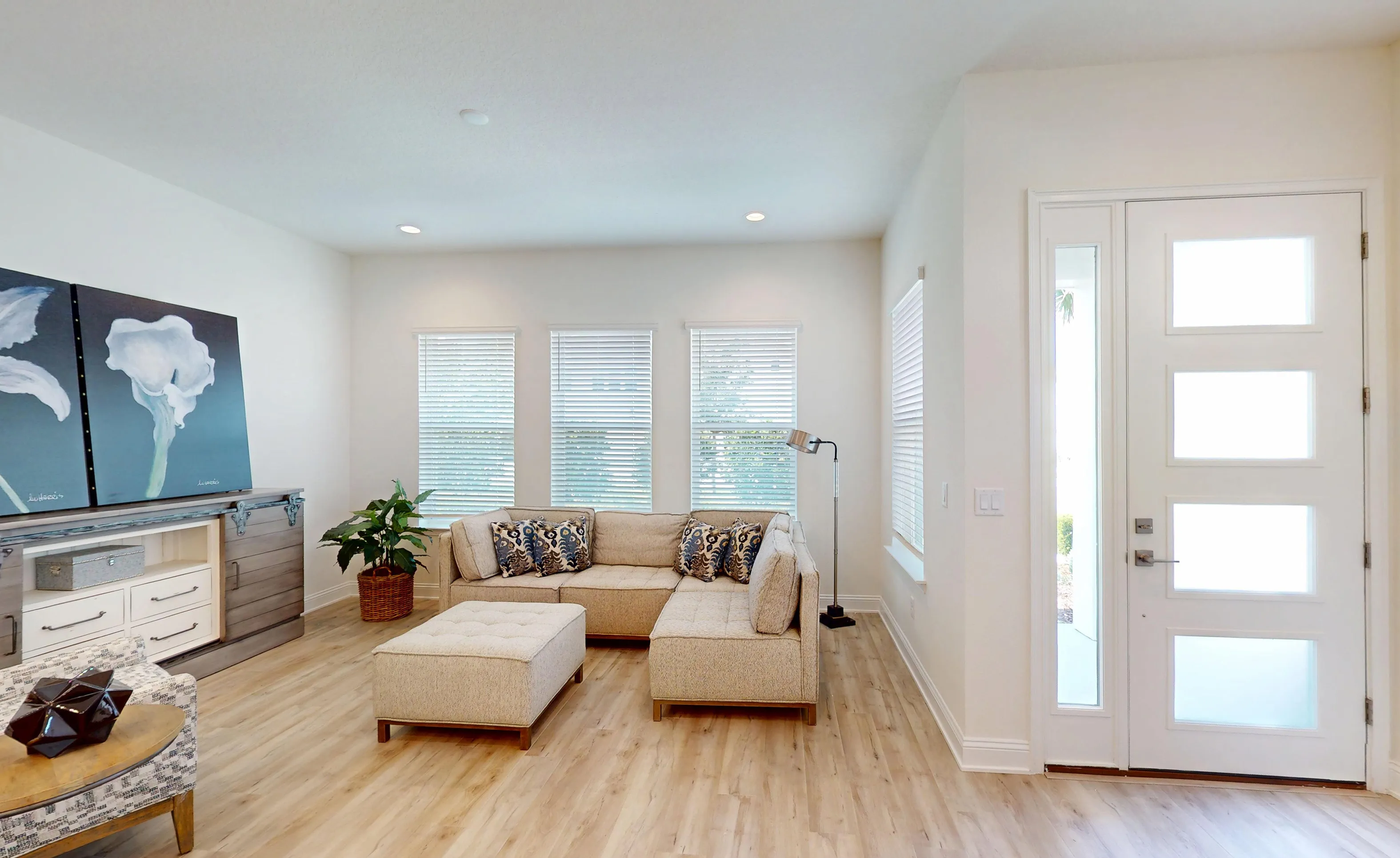 Foyer of the Bartram model in Nocatee featuring a white front door with glass panels, beige sectional, and light flooring.