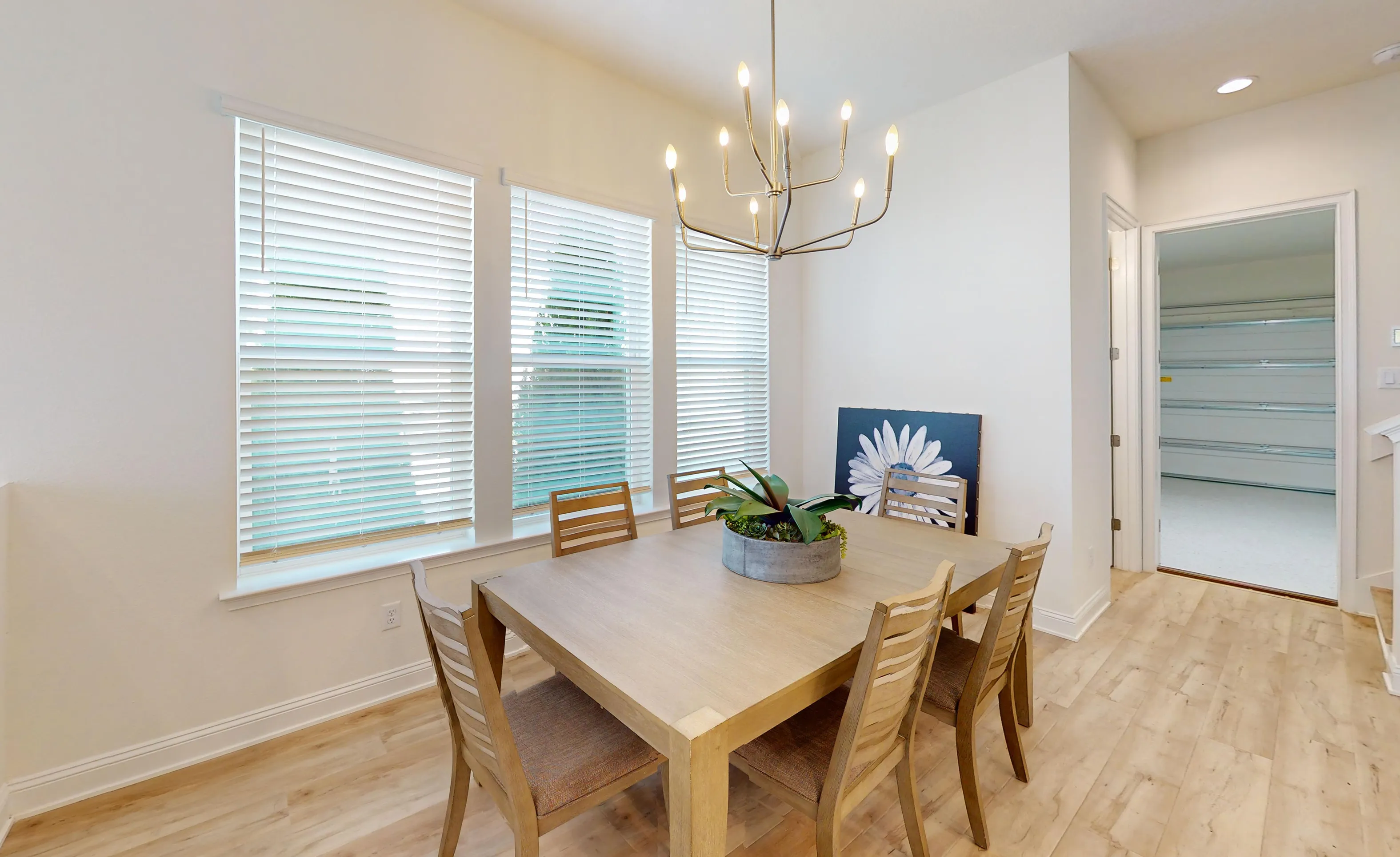 Dining room in the Bartram floor plan with light wood flooring, a wooden dining table, and a modern chandelier.
