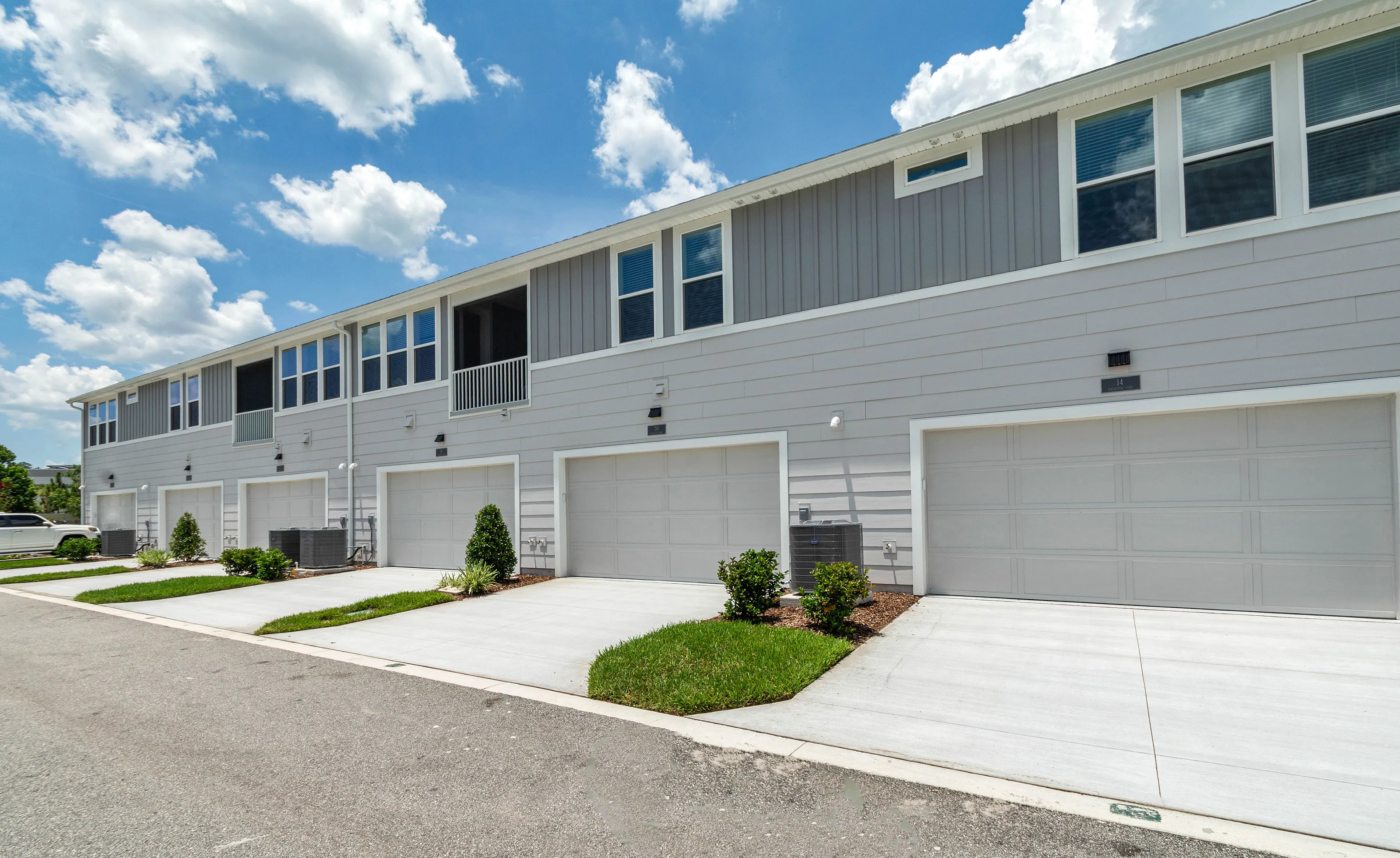 Front exterior of the Castillo C townhouse in Nocatee featuring grey siding, multiple garages, and concrete driveways.