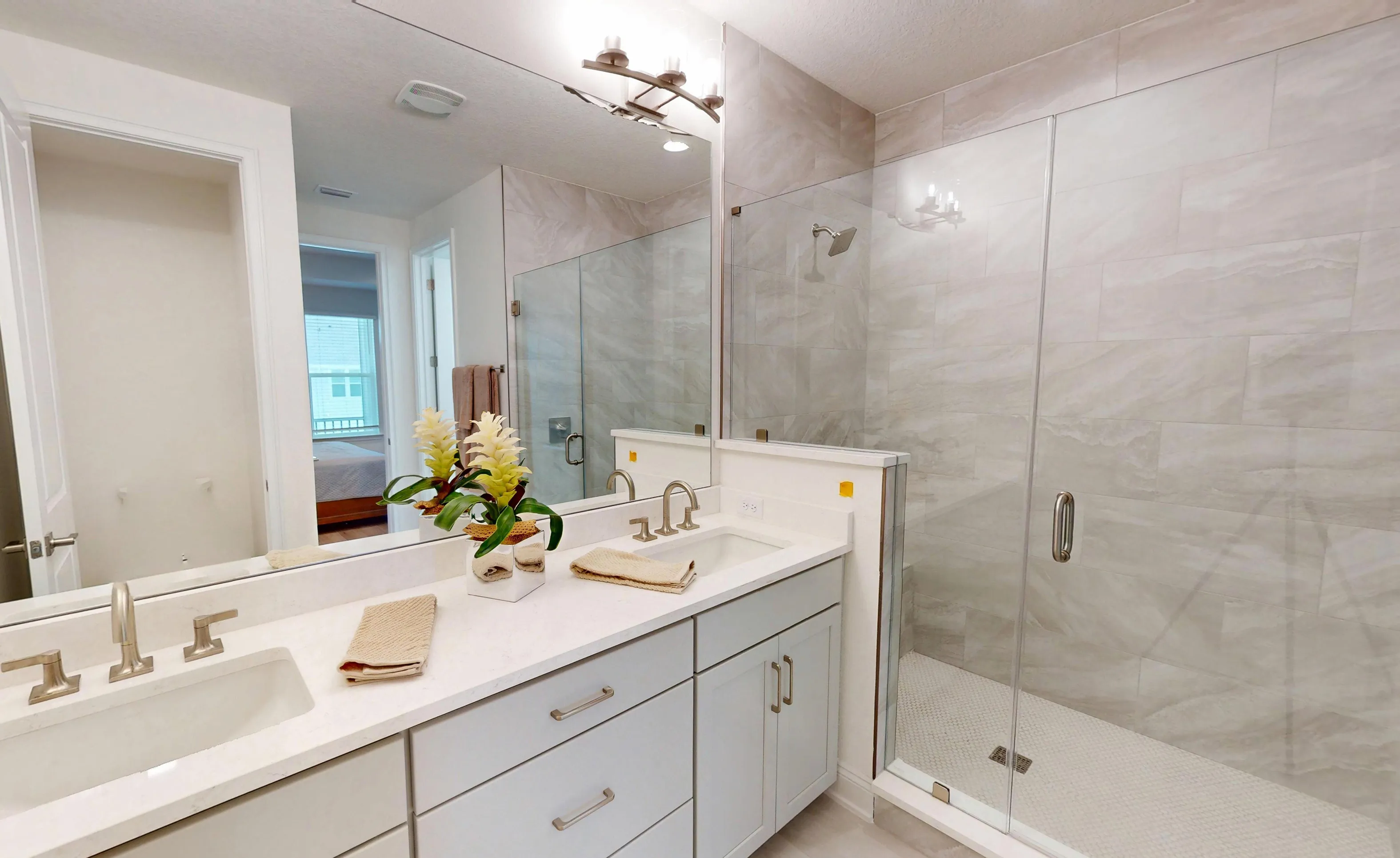 Primary bath in the Castillo plan with a double vanity, light gray cabinets, and a walk-in shower with tiled walls.