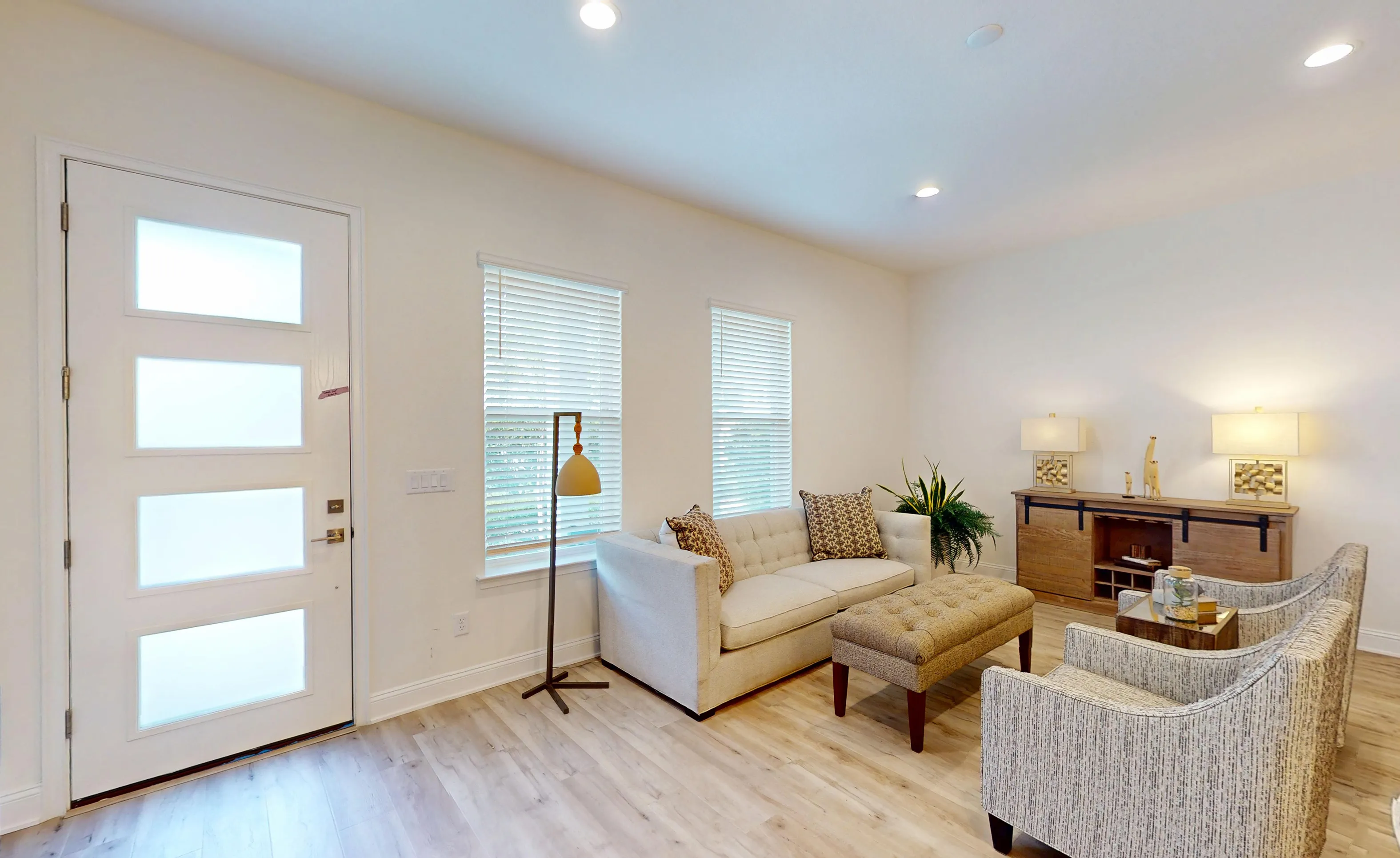 Foyer of the Deleon plan in Nocatee featuring a white door with frosted glass panels, light wood floors, and seating area.