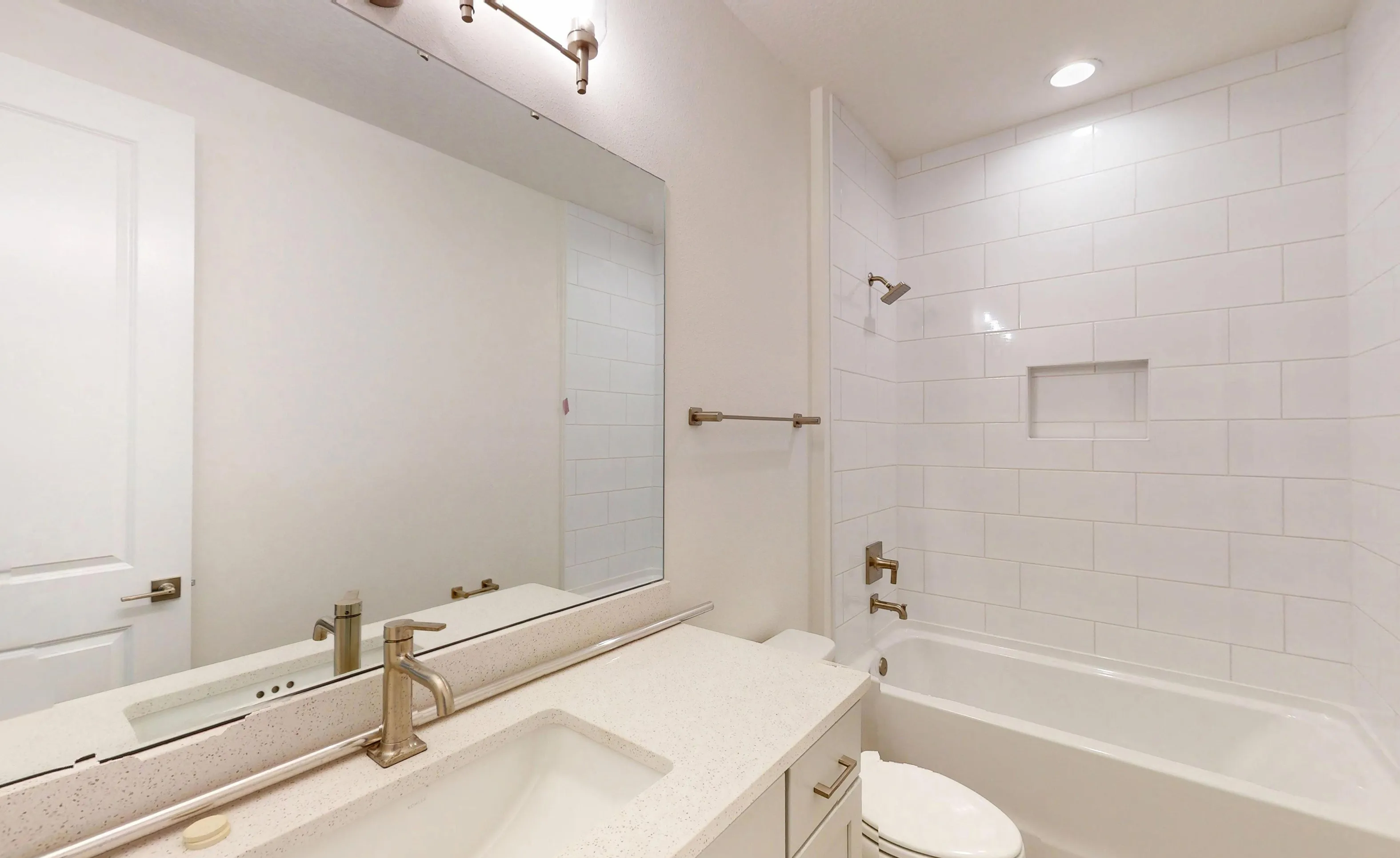 Secondary bathroom with a white vanity, countertop, single sink, wall-to-wall mirror, and a tub-shower with white tile.