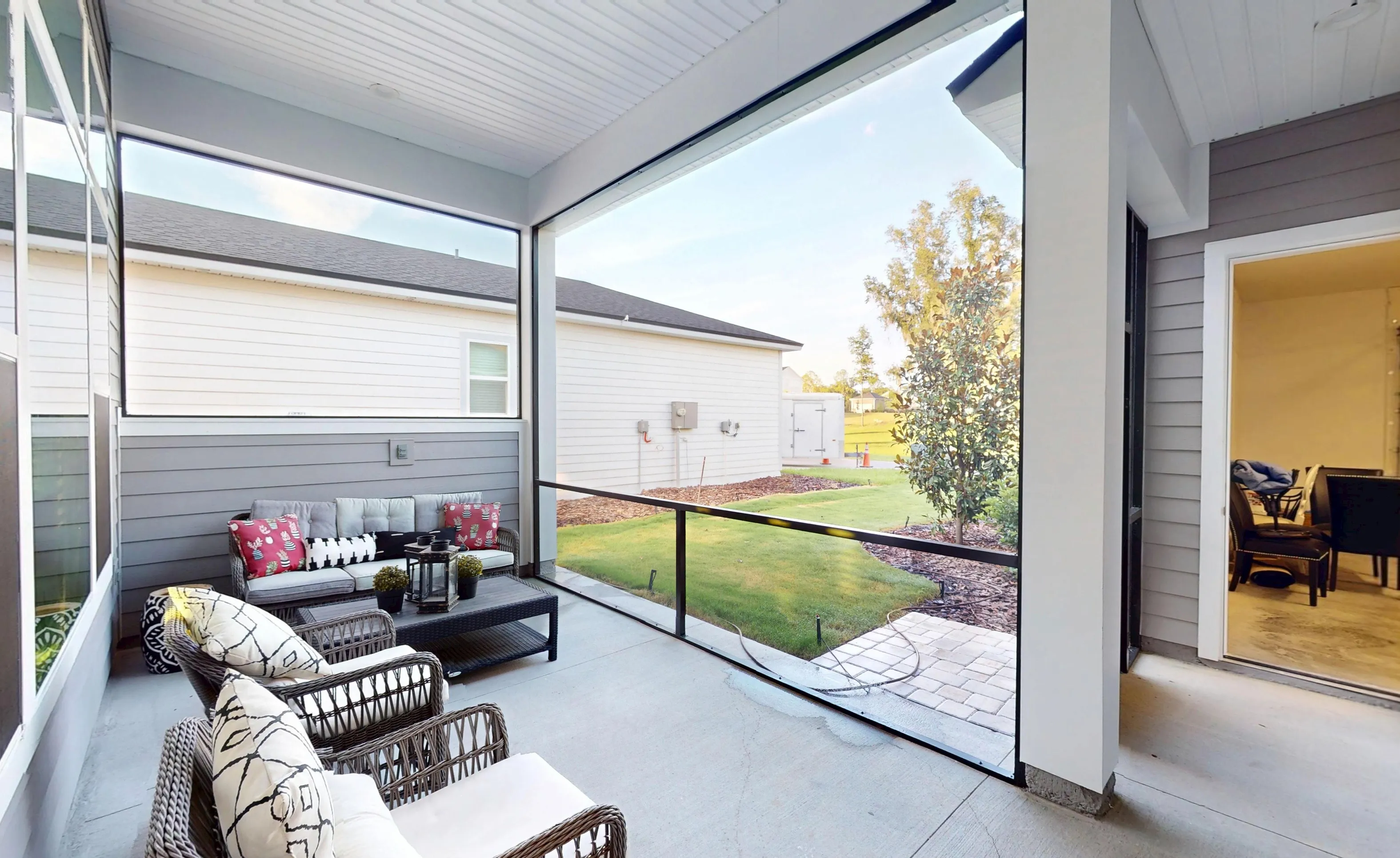 Screened lanai of a Kona home featuring gray siding, patio furniture, and a view of the backyard.