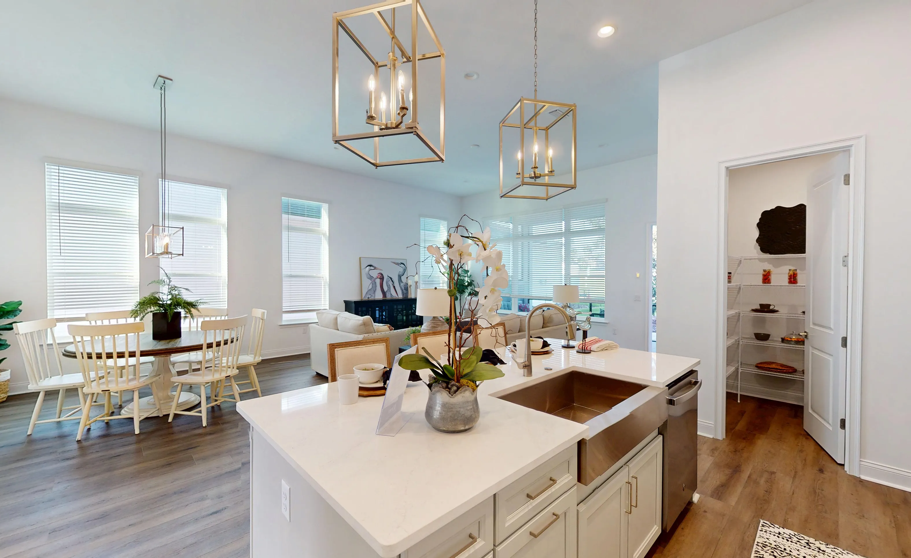 Kitchen island with white countertop and farmhouse sink in the Kona floor plan with dining area and walk-in pantry.