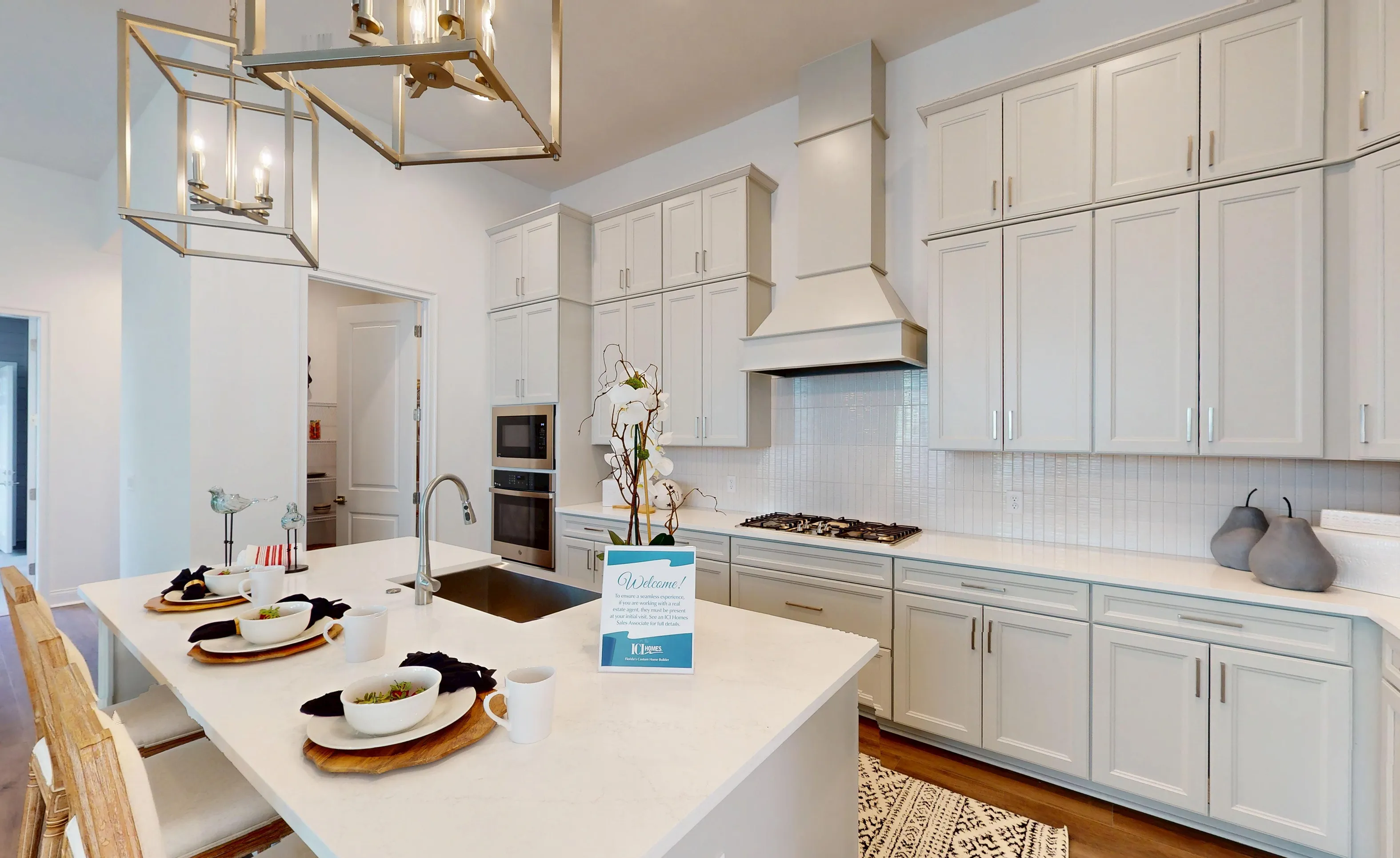 Kona plan kitchen in Oakmont with white shaker cabinets, quartz countertops, a large island, and stainless steel appliances.