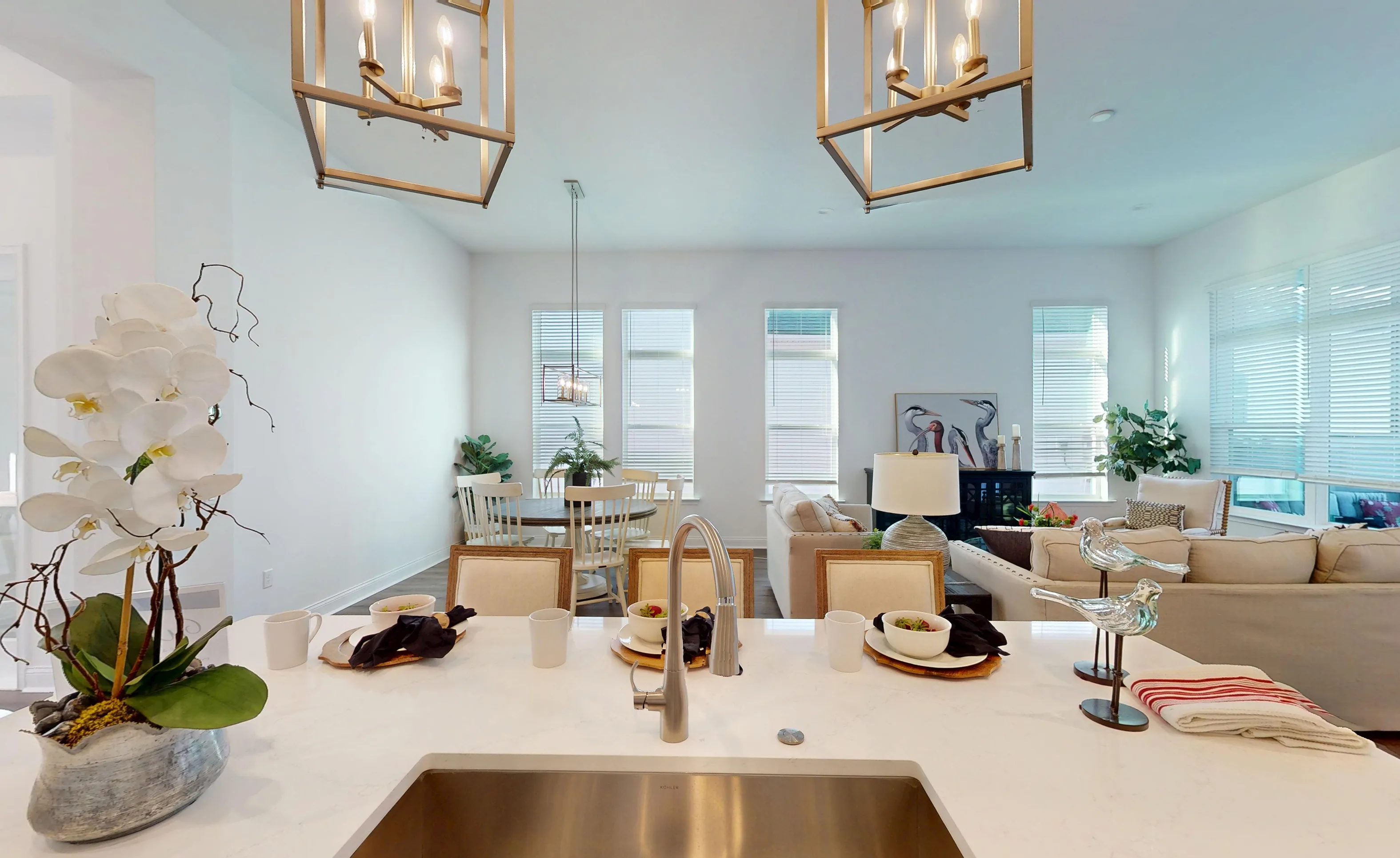 Kitchen island with white countertop and sink overlooking the dining area and living room in the Kona model home.