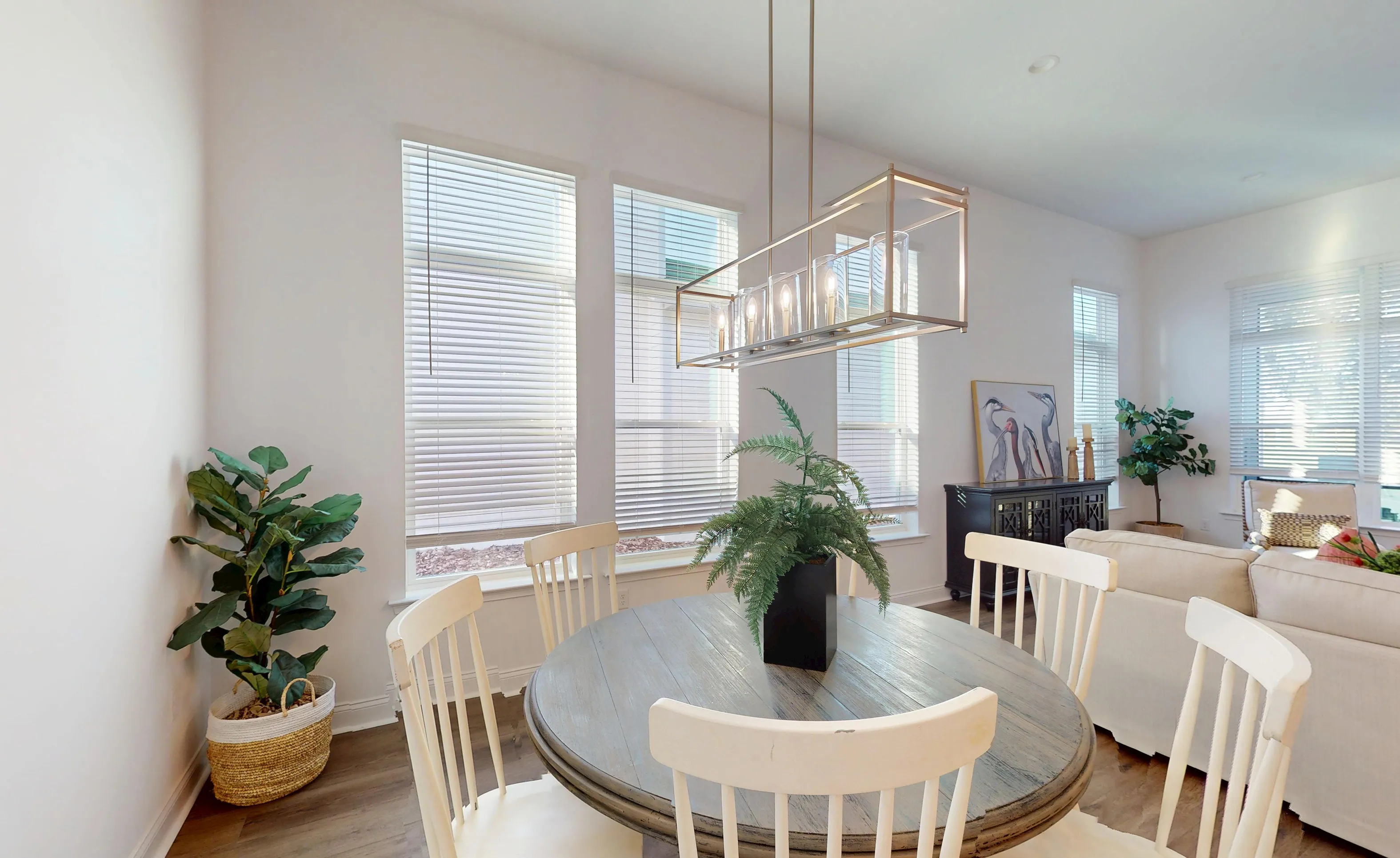 Breakfast nook in the Kona plan featuring a round wooden table, white spindle chairs, and a rectangular pendant light.