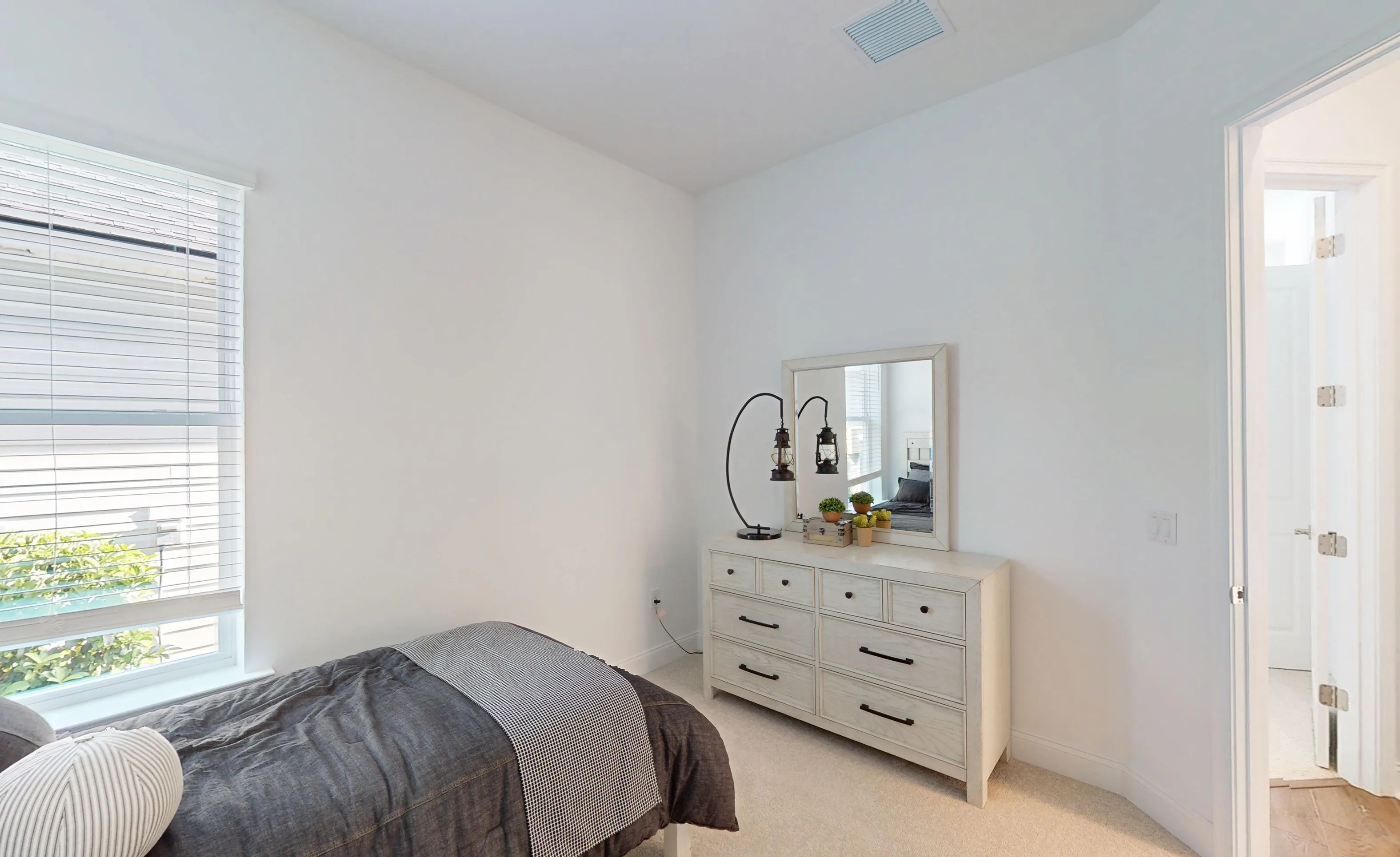 Secondary bedroom in the Kona plan featuring white walls, carpeted floors, a window with blinds, and a white dresser.