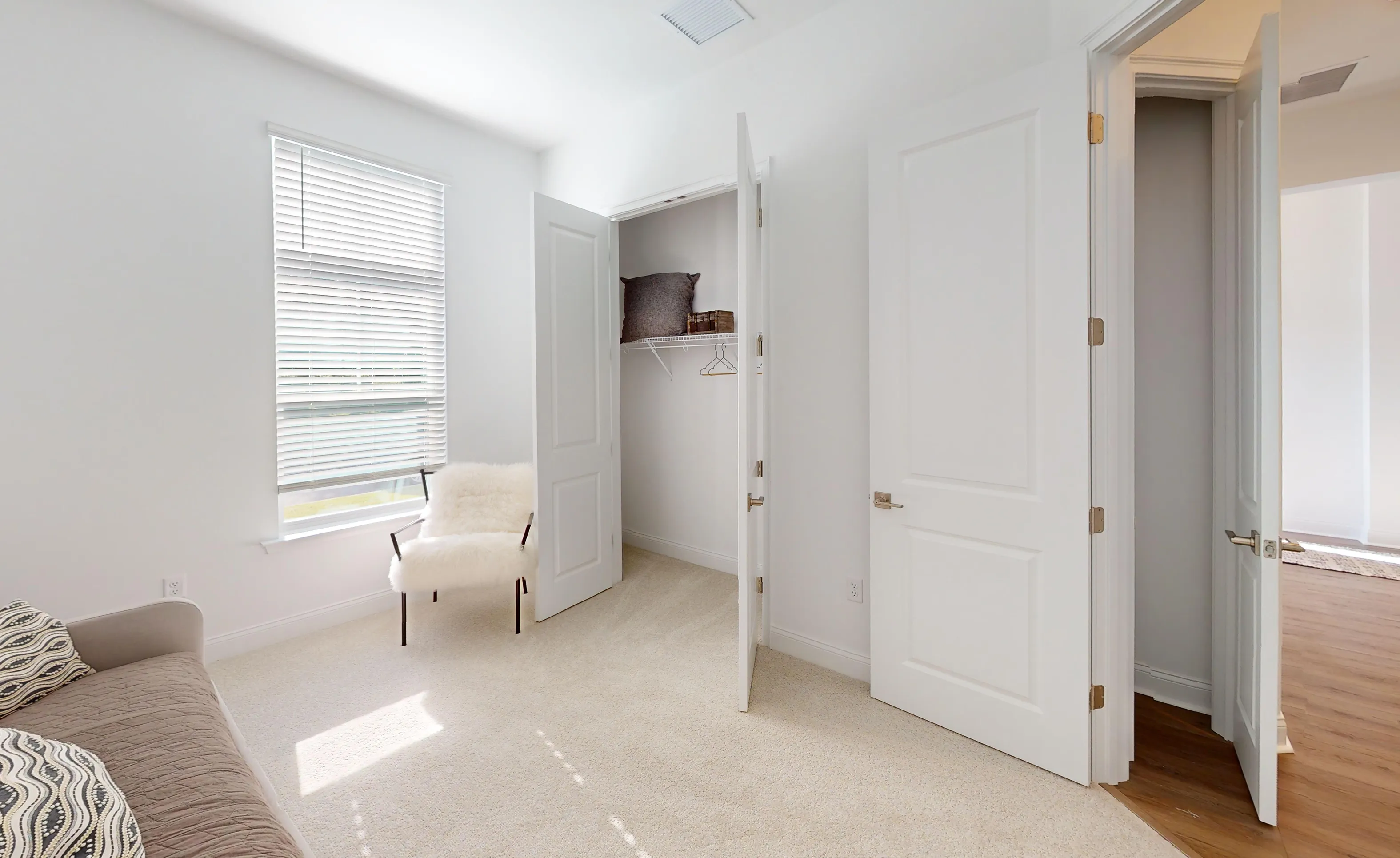 Secondary bedroom in the Kona plan with white walls, carpet, a window with blinds, a reach-in closet, and an open door.
