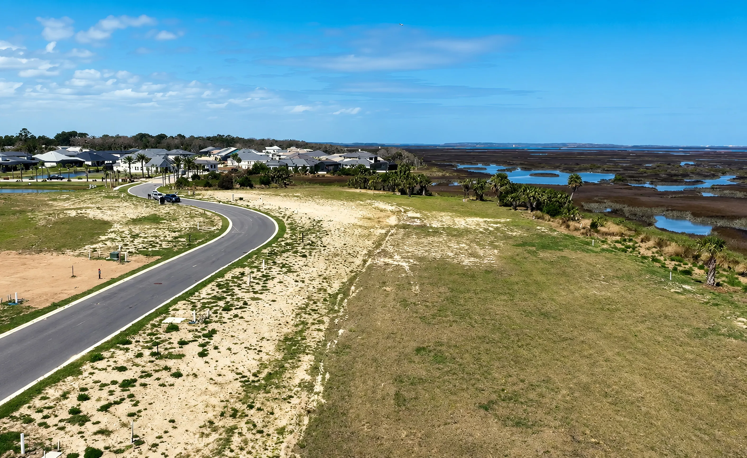 Aerial view of Madeira at St. Augustine community showing a winding road, new residential lots, and surrounding wetlands.