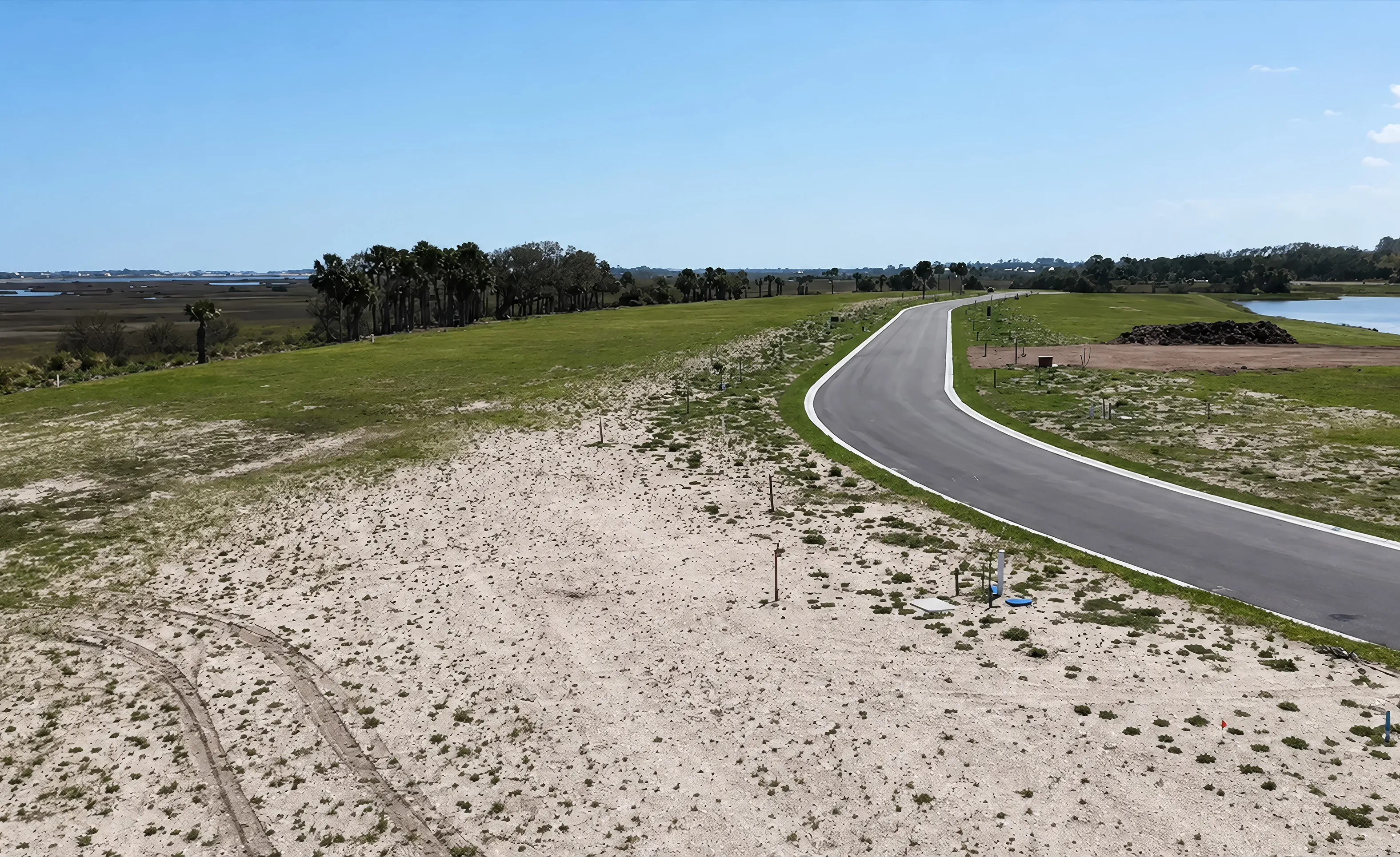 Aerial view of a paved road winding through undeveloped land in Madeira at St. Augustine, featuring wetlands and trees.
