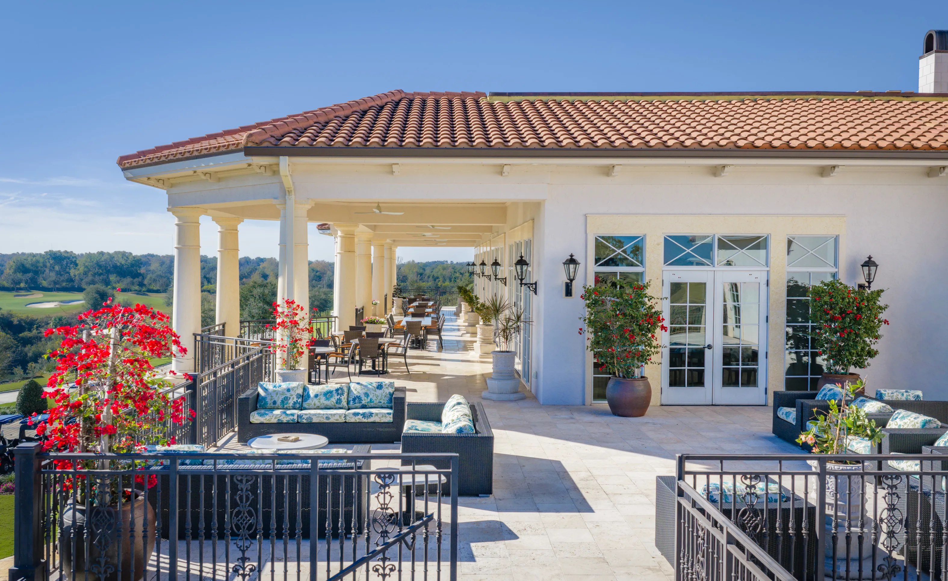 Spacious covered patio at IronCrest featuring tile roofing, stone flooring, classical columns, and outdoor lounge furniture.