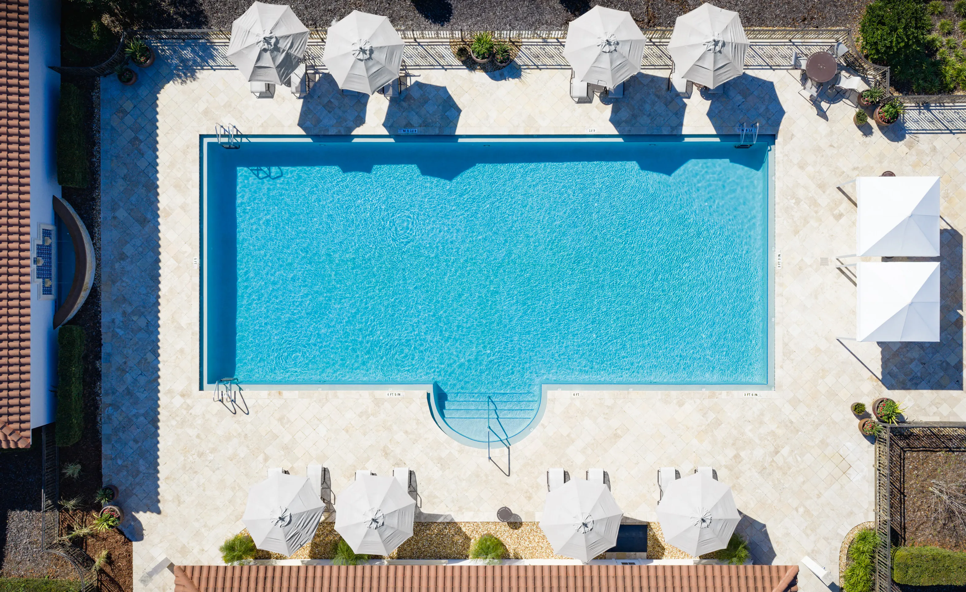 Aerial view of the IronCrest community swimming pool surrounded by a stone deck, lounge chairs, and white umbrellas.