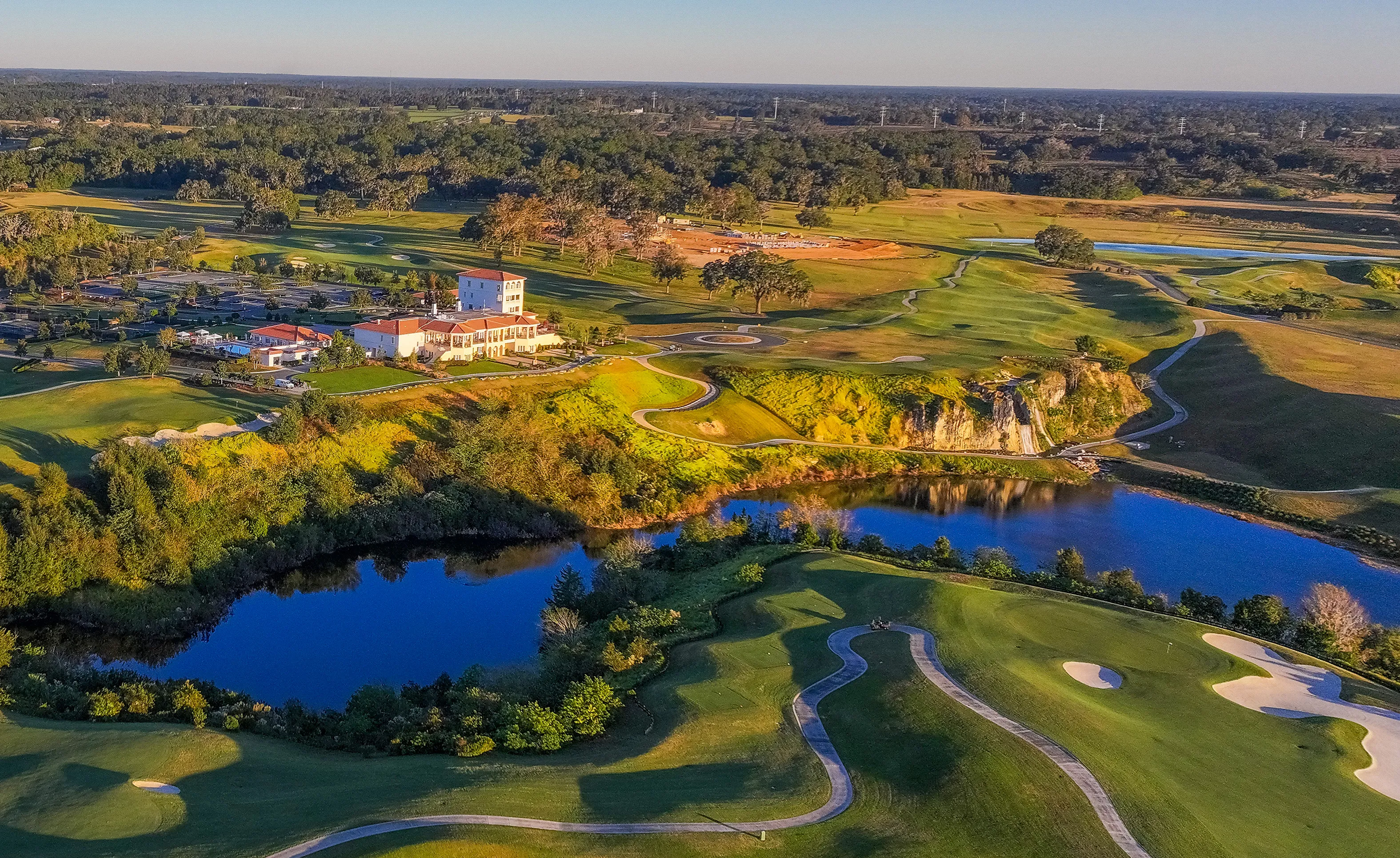 Aerial view of the IronCrest community featuring a large clubhouse, winding golf course paths, a pond, and rocky terrain.