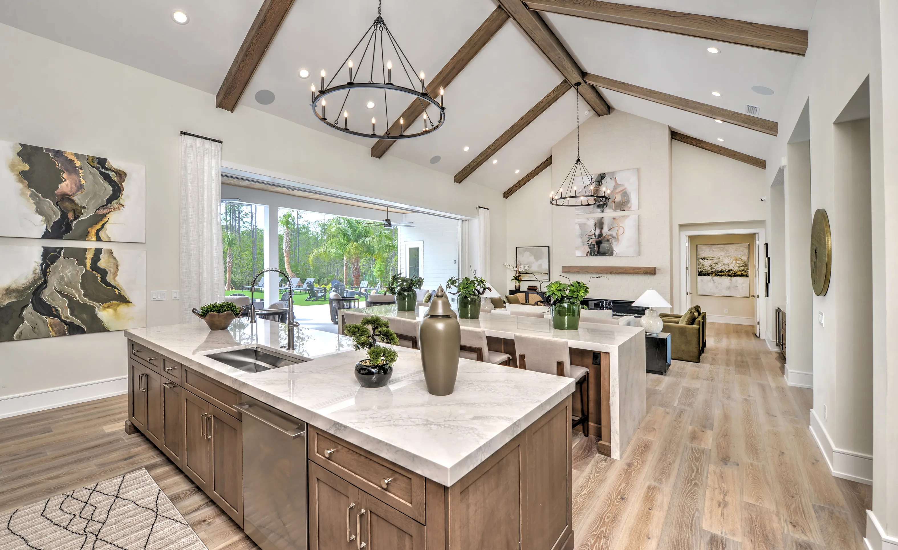Courtney Grove open concept kitchen with wood beamed vaulted ceilings, marble island, and view to a covered patio.