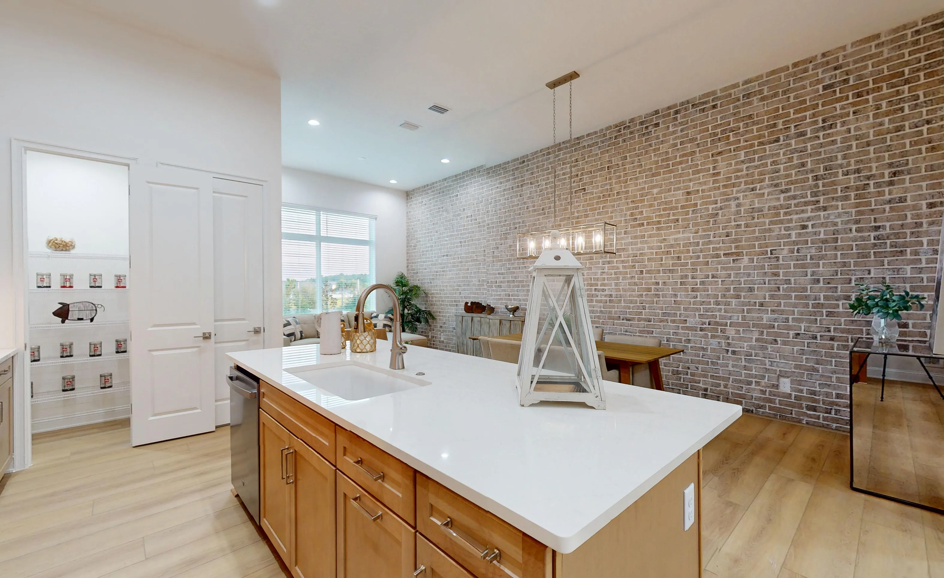 Kitchen with a central island featuring a white countertop, wooden cabinets, and an adjacent pantry in the Nocatee home.