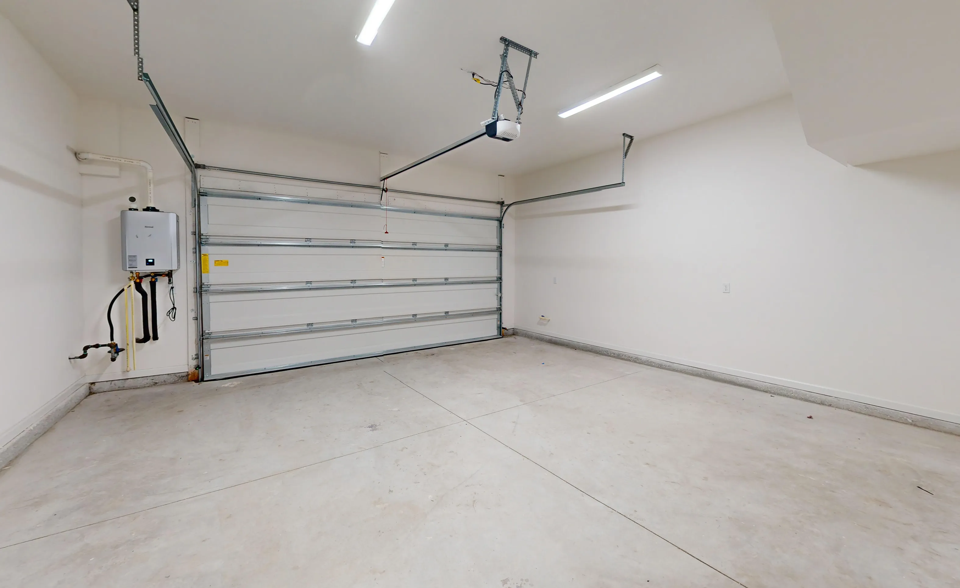 Interior of a spacious, unfinished garage in the Nocatee community with white walls, a concrete floor, and water heater.