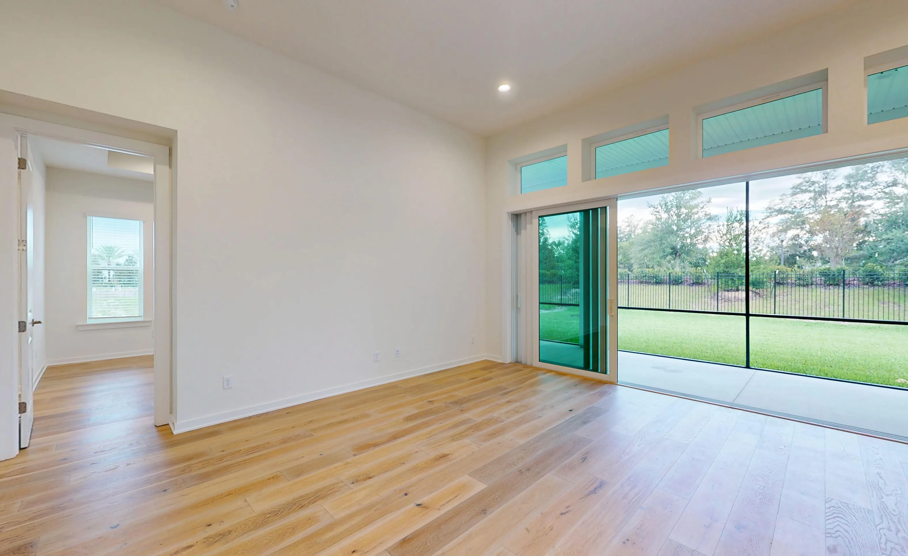 Living room of the Palos Verdes plan with wood-look flooring, a large sliding glass door, and a view of a screened patio.