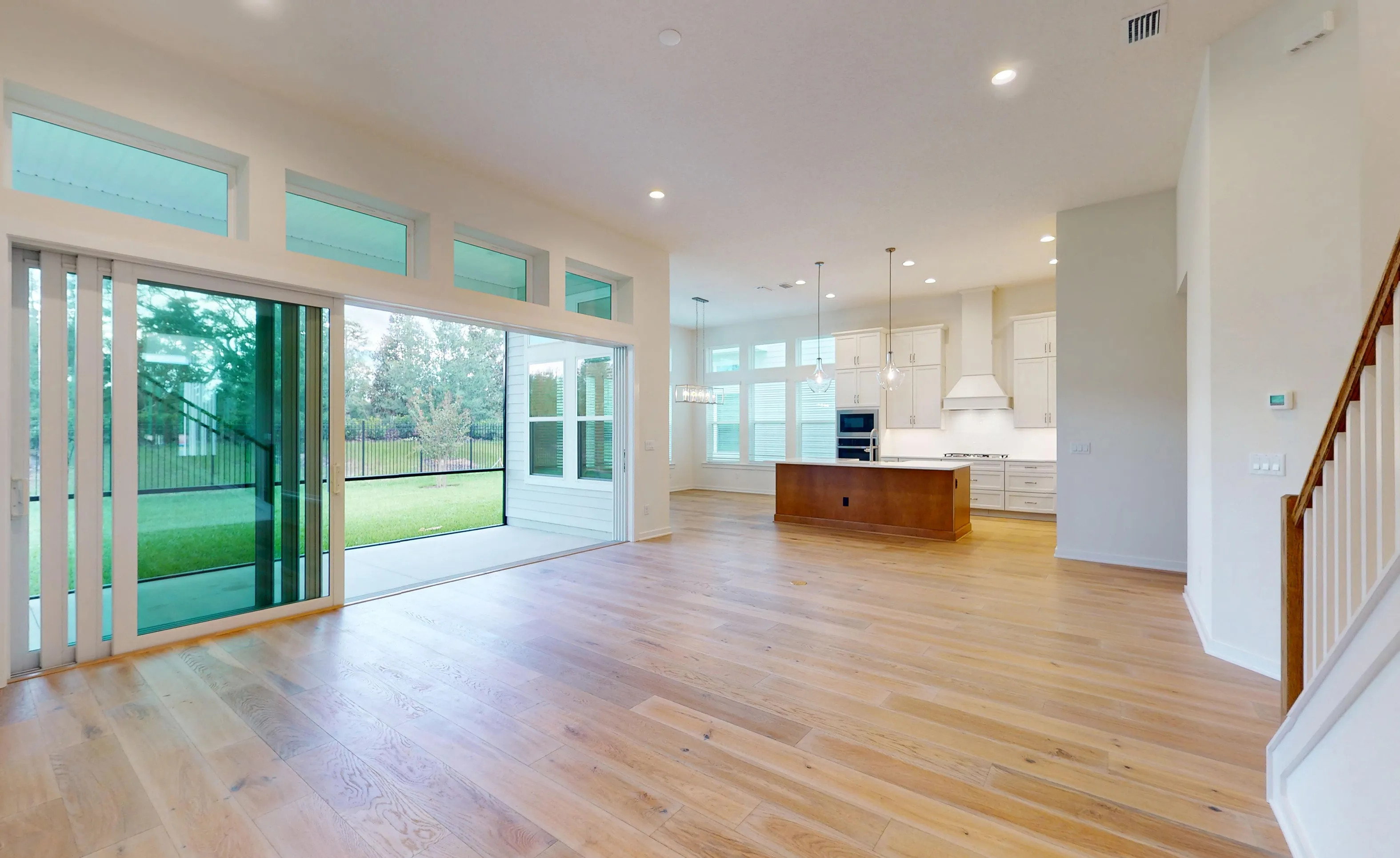 Open-concept Palos Verdes living room with wood floors, sliding glass wall to a patio, and view of the kitchen island.