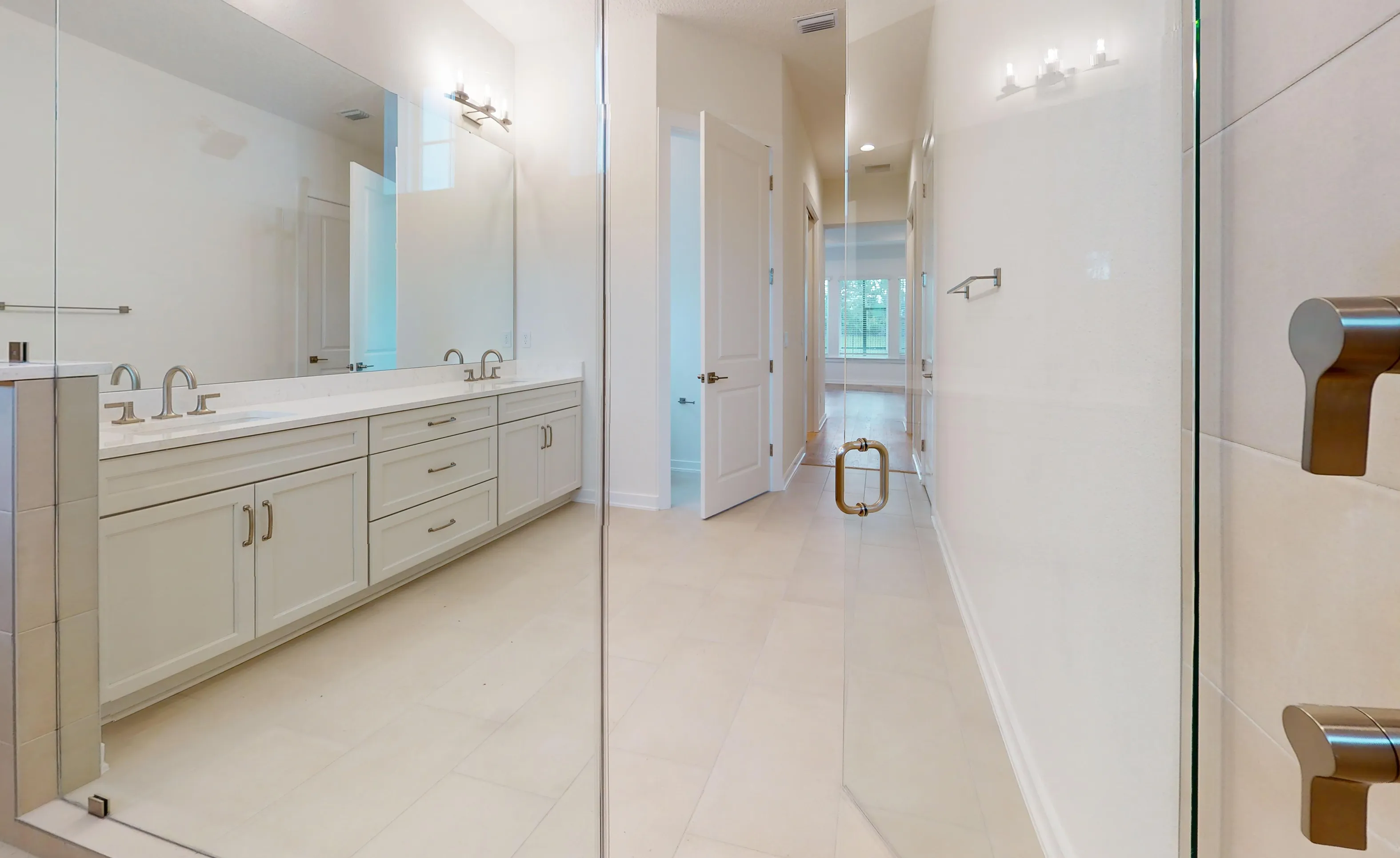 Primary bath in the Palos Verdes plan featuring a double vanity with light cabinets, a large mirror, and glass shower door.