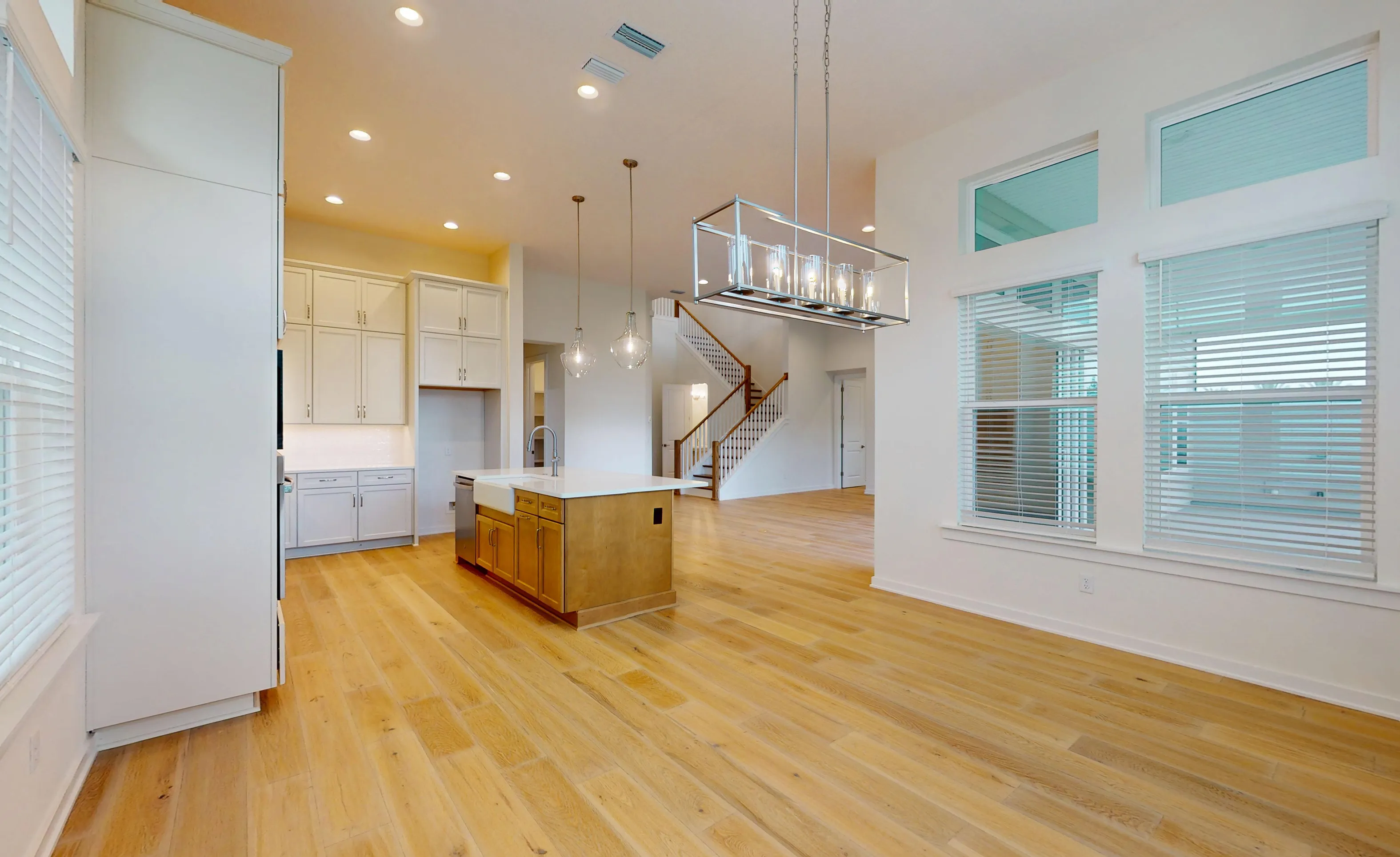 Palos Verdes kitchen with white cabinets, wood island, farmhouse sink, hardwood floors, and a view of the staircase.