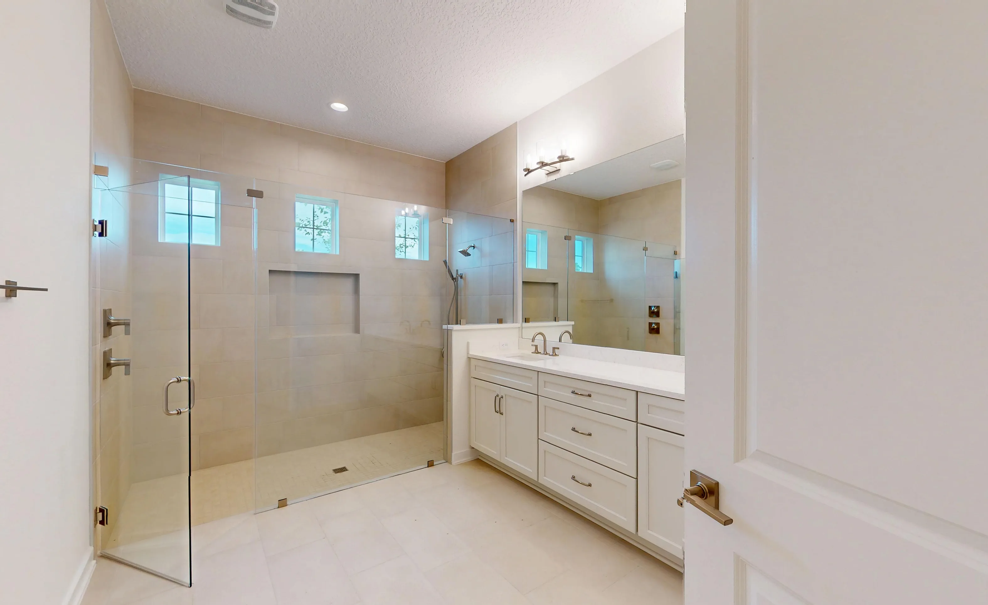 Primary bath in the Palos Verdes plan featuring a glass-enclosed walk-in tile shower and a white dual-sink vanity.