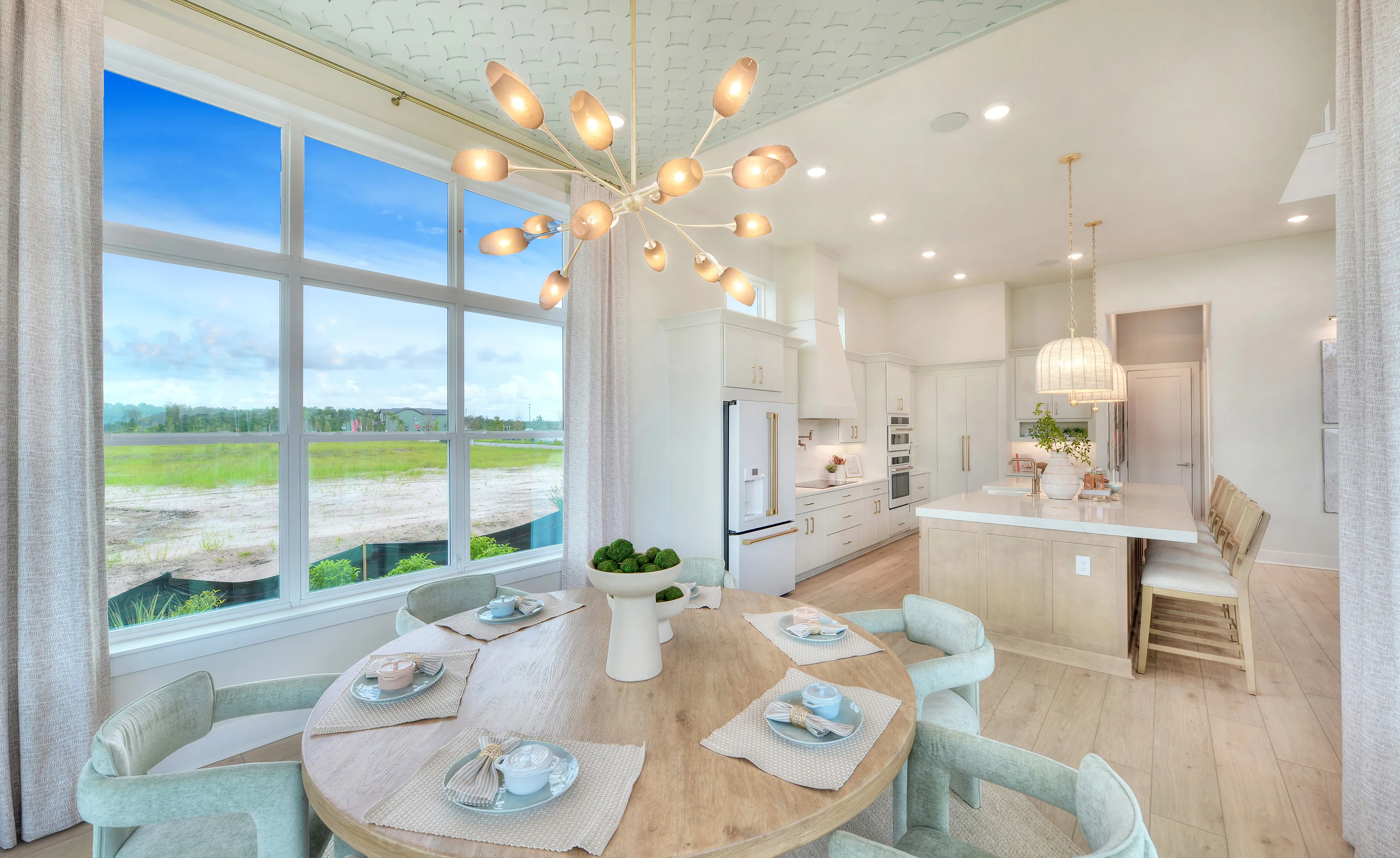 Dining Room with a round wood table and light green chairs, featuring a modern chandelier under a patterned ceiling.
