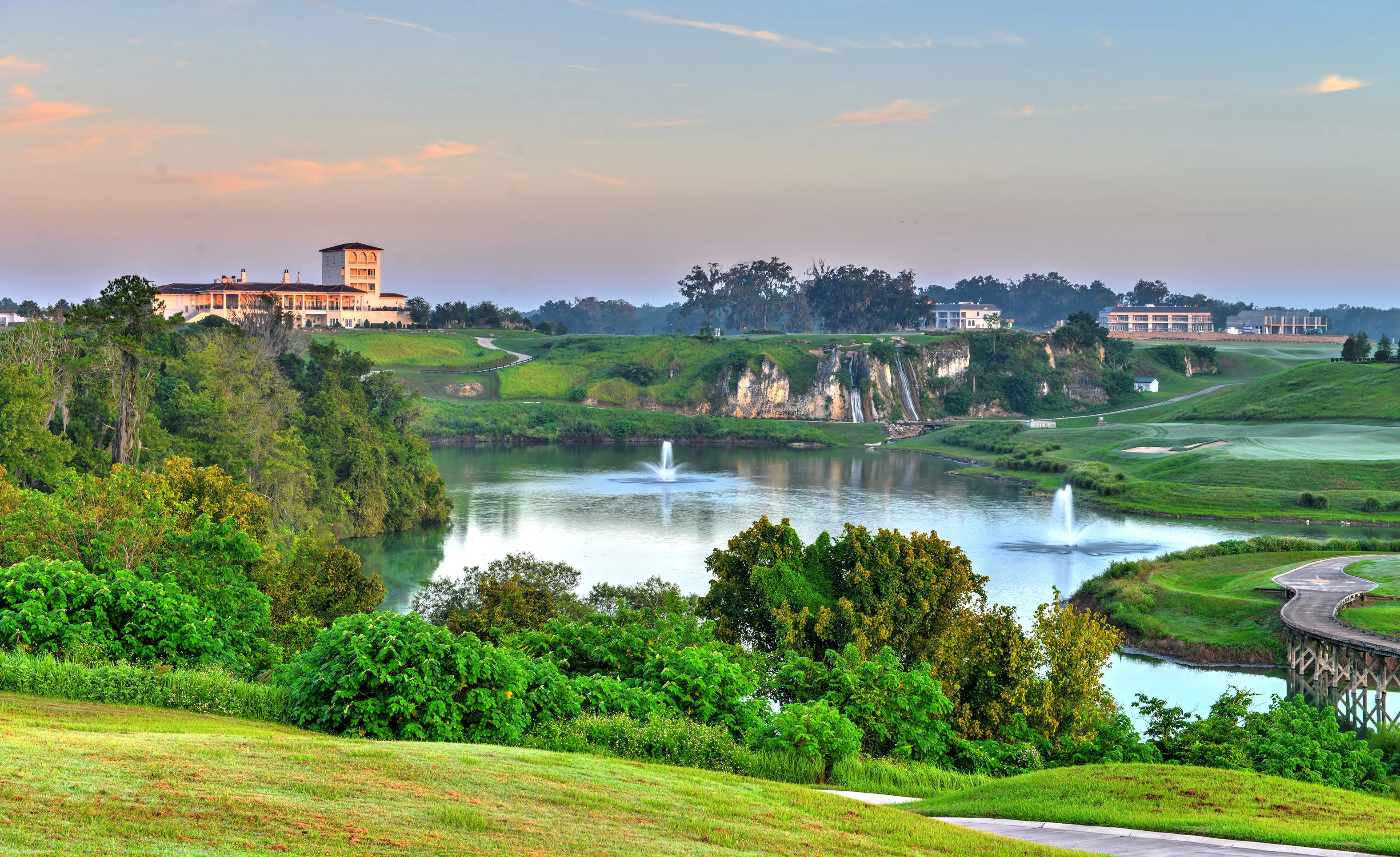 View of a lake with fountains, waterfalls, and a clubhouse at the IronCrest community.