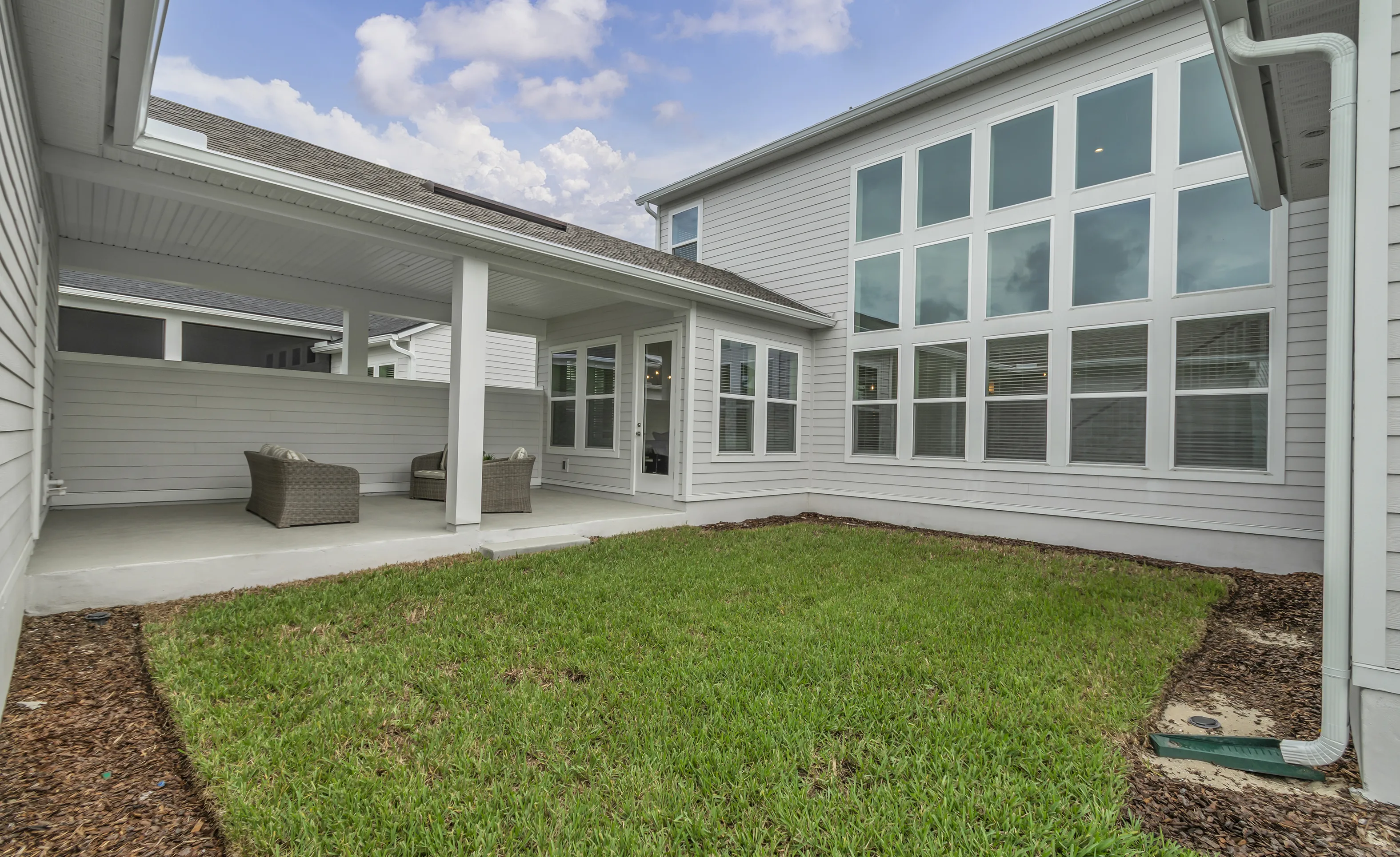 Covered porch of a Braddock plan home at Seven Pines featuring white siding, a concrete floor, and two outdoor chairs.