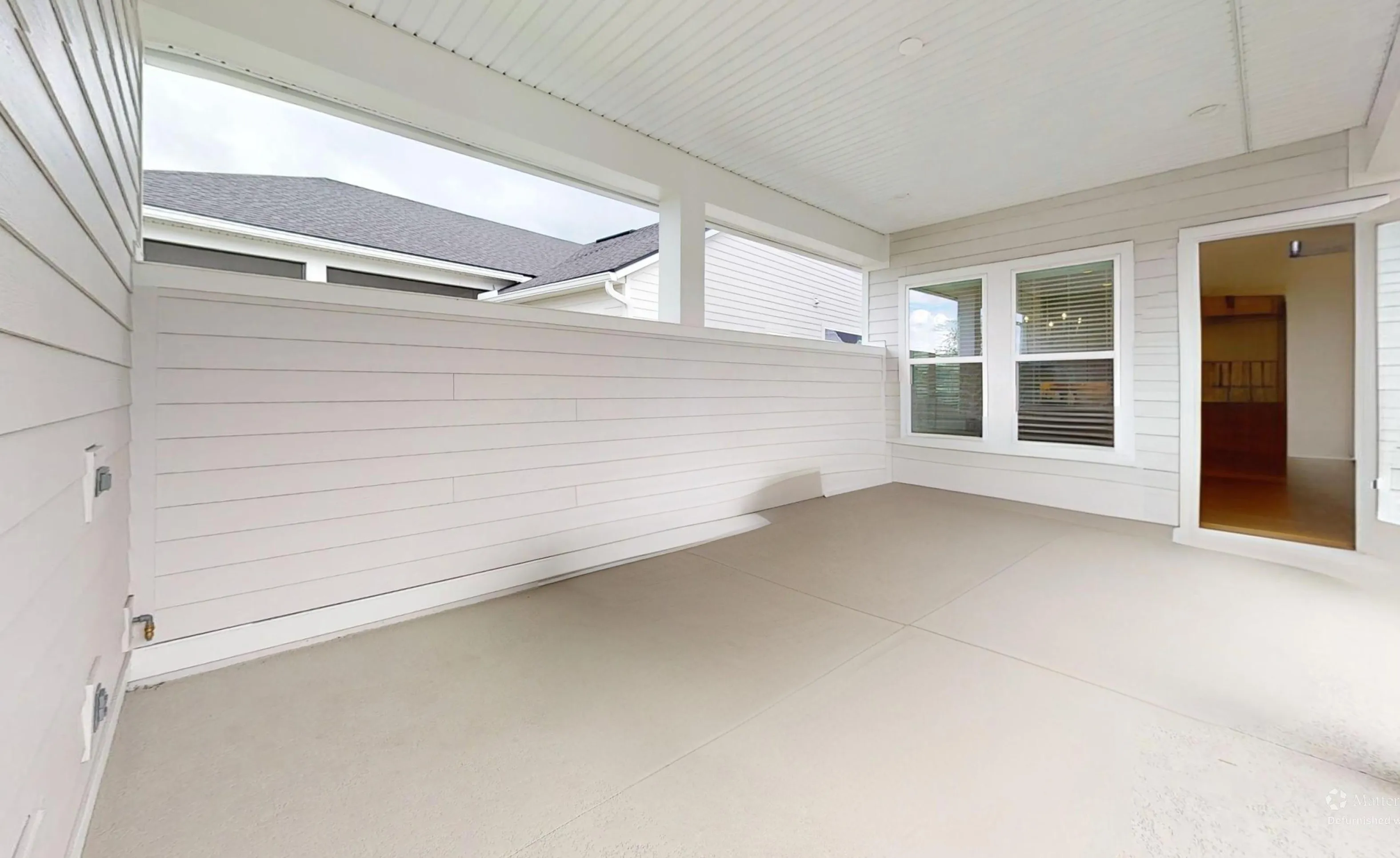 Covered porch with white horizontal siding walls, a concrete floor, and an entryway leading into the home.