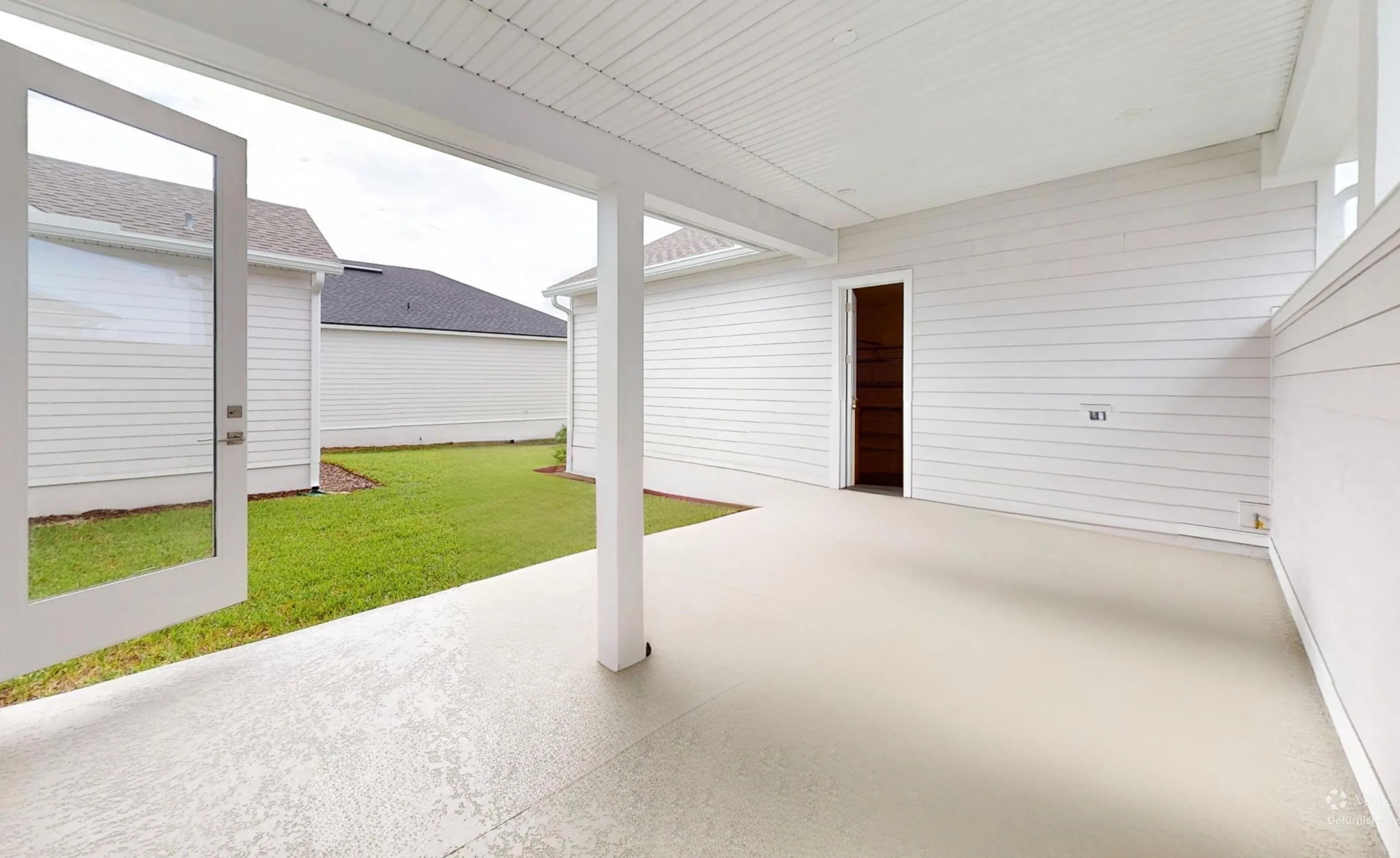 Covered porch of the Braddock plan with white siding, a single support column, concrete floor, and an open doorway.