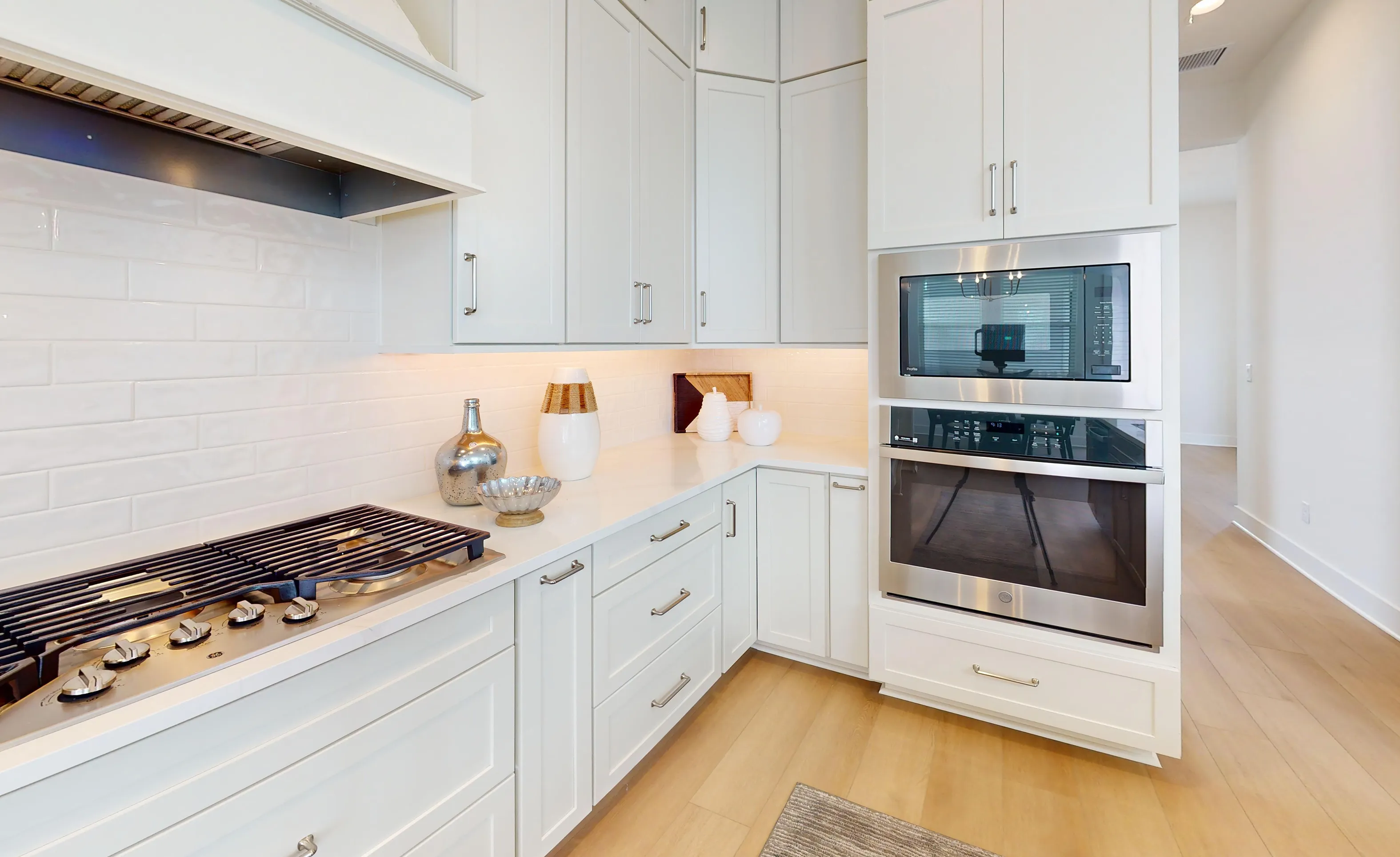 Braddock plan kitchen in Seven Pines featuring white cabinets, subway tile backsplash, gas cooktop, and stainless wall ovens.