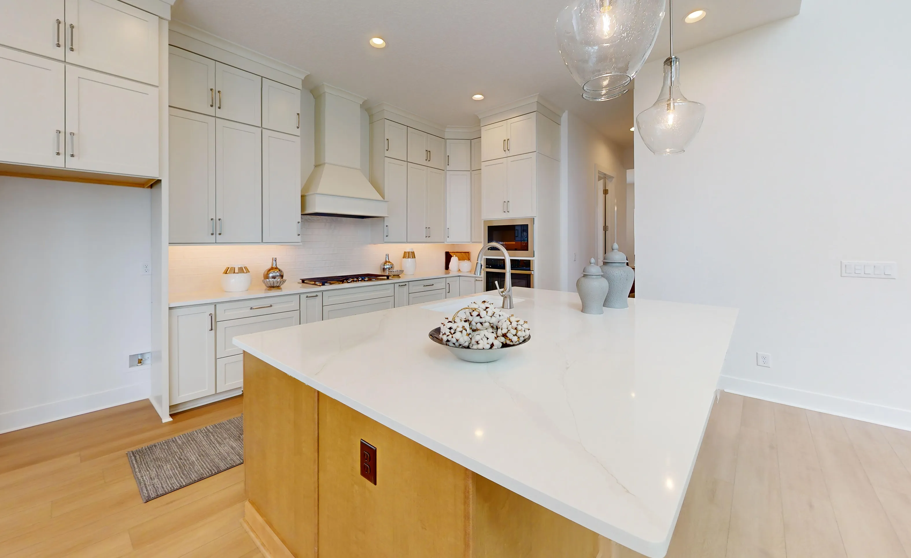 Braddock plan kitchen at Seven Pines featuring light-colored cabinets, a white quartz island, and glass pendant lights.