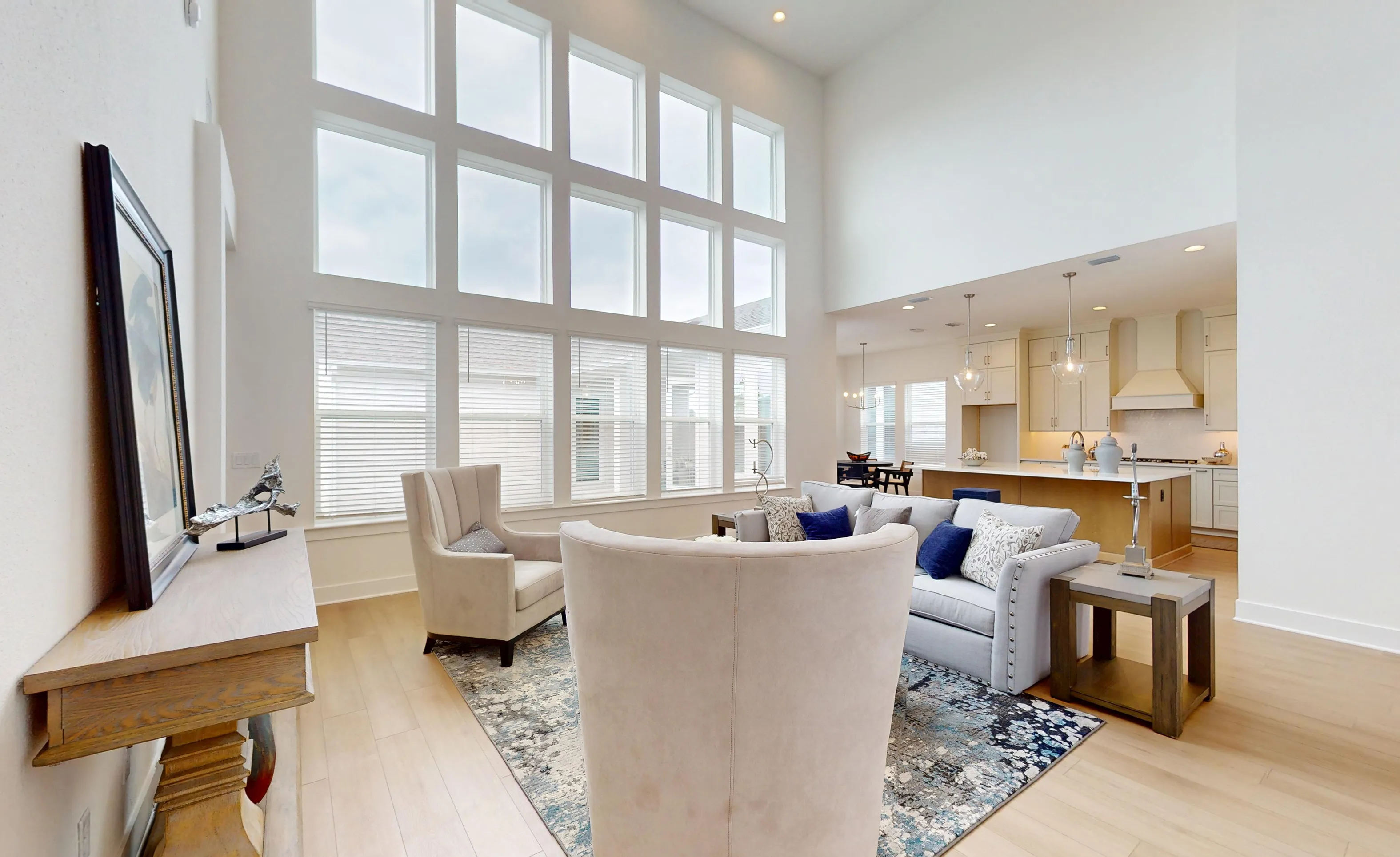 Living room of the Braddock plan with tall windows, light wood floors, and an open floor plan leading to the kitchen.
