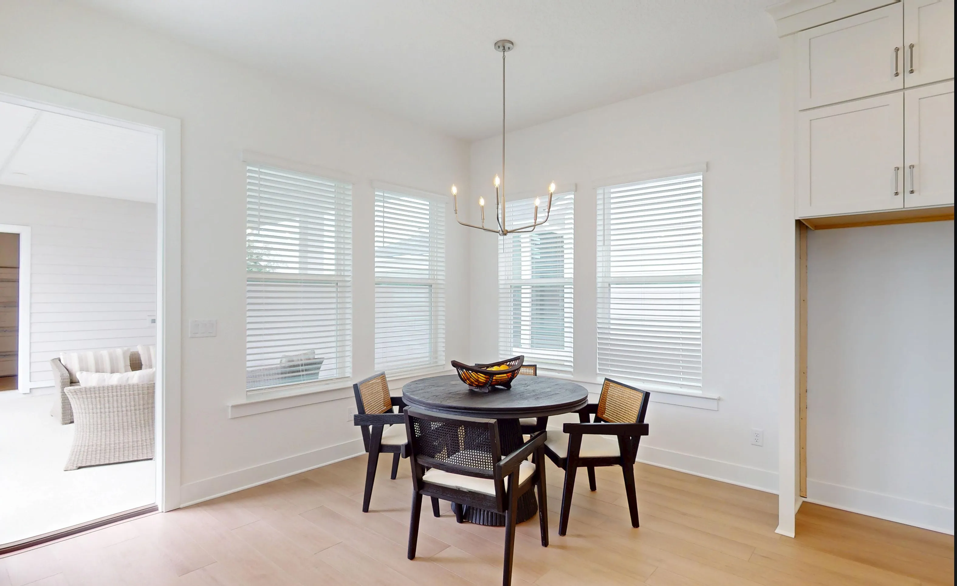 Breakfast nook in the Braddock plan with a round black table, cane-back chairs, four windows, and a metal chandelier.