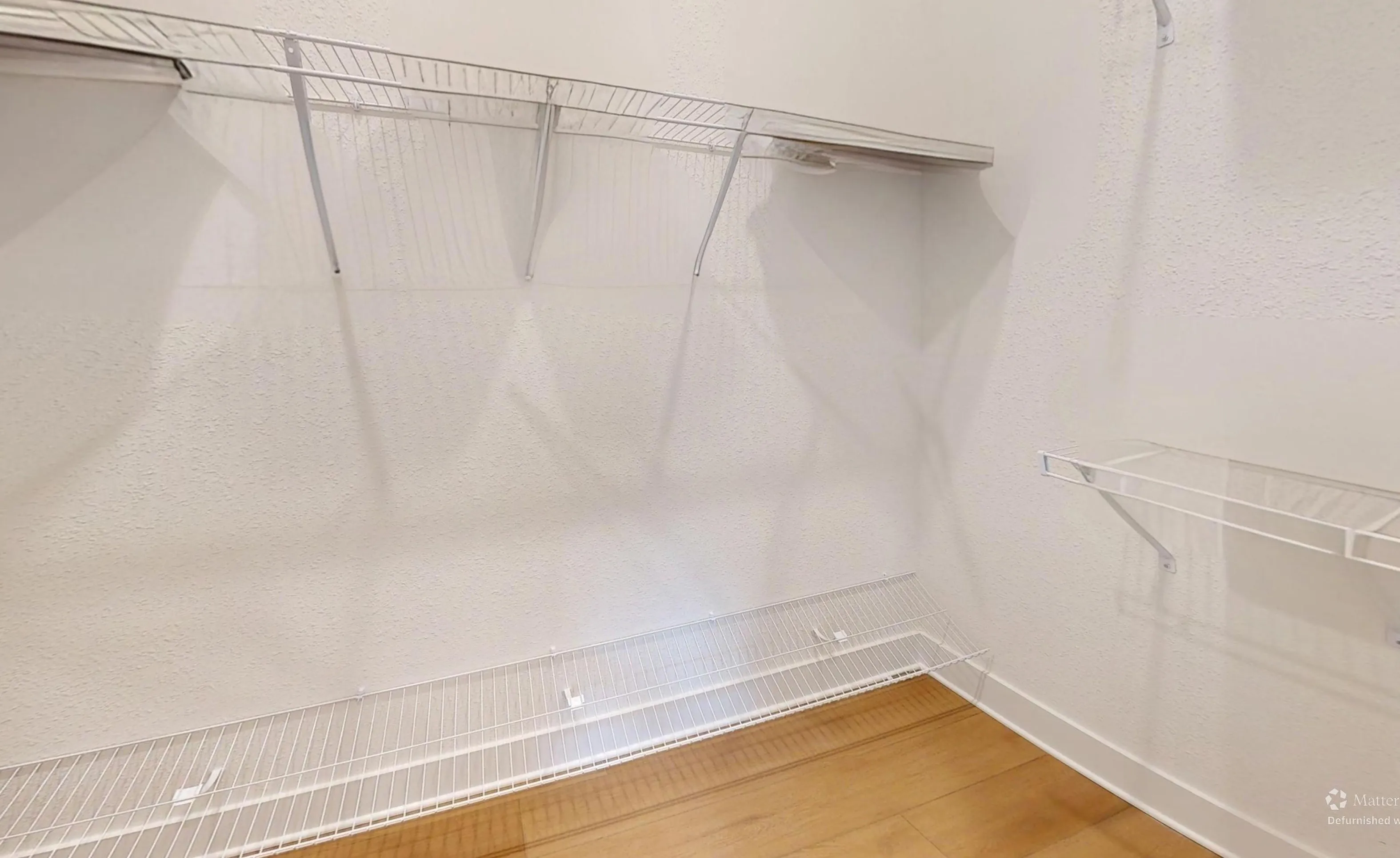 Walk-in closet in the Braddock home featuring white walls, wood-look flooring, and white wire shelving.