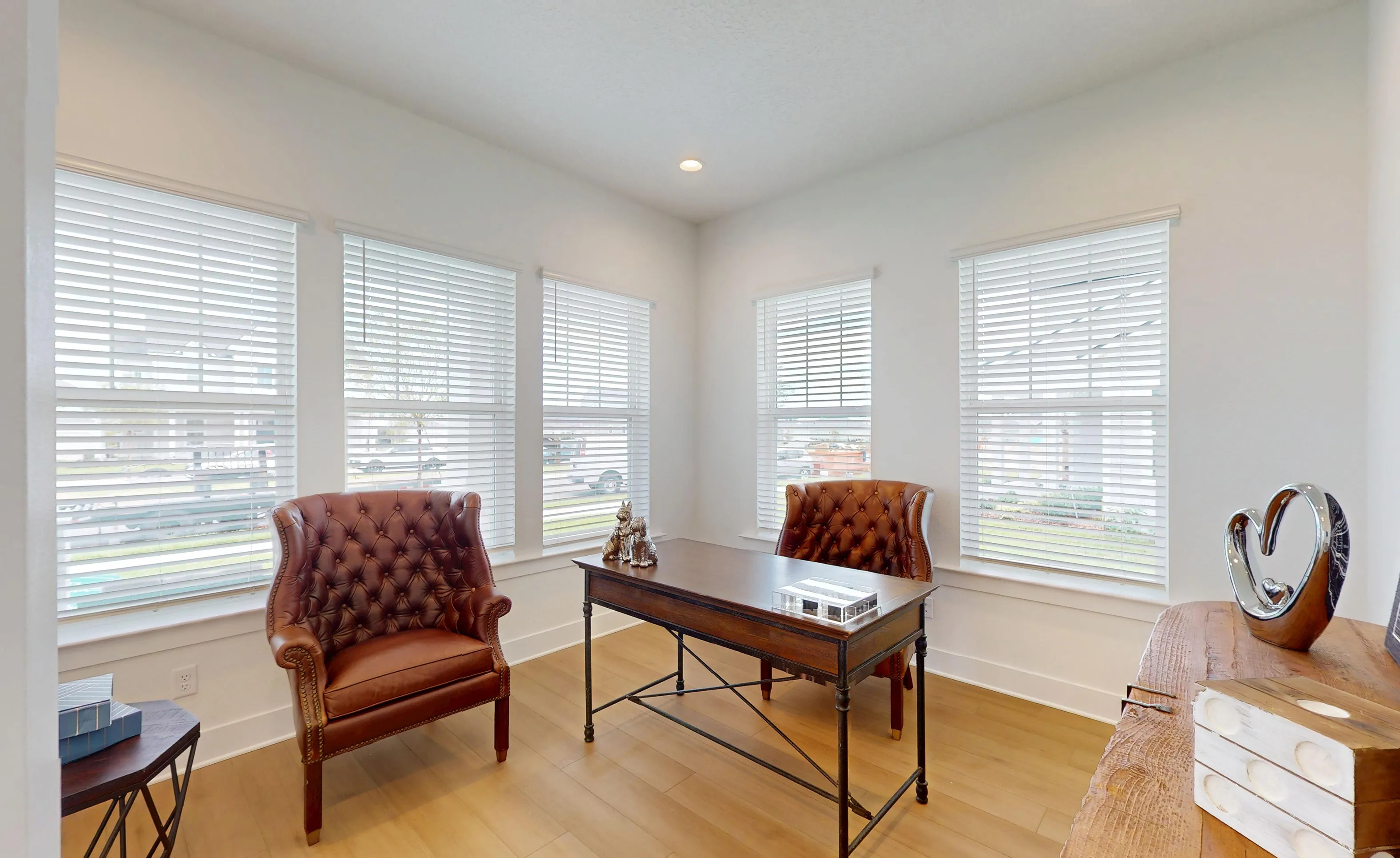 Home office of the Braddock plan at Seven Pines with white walls, light wood floors, and five windows with white blinds.