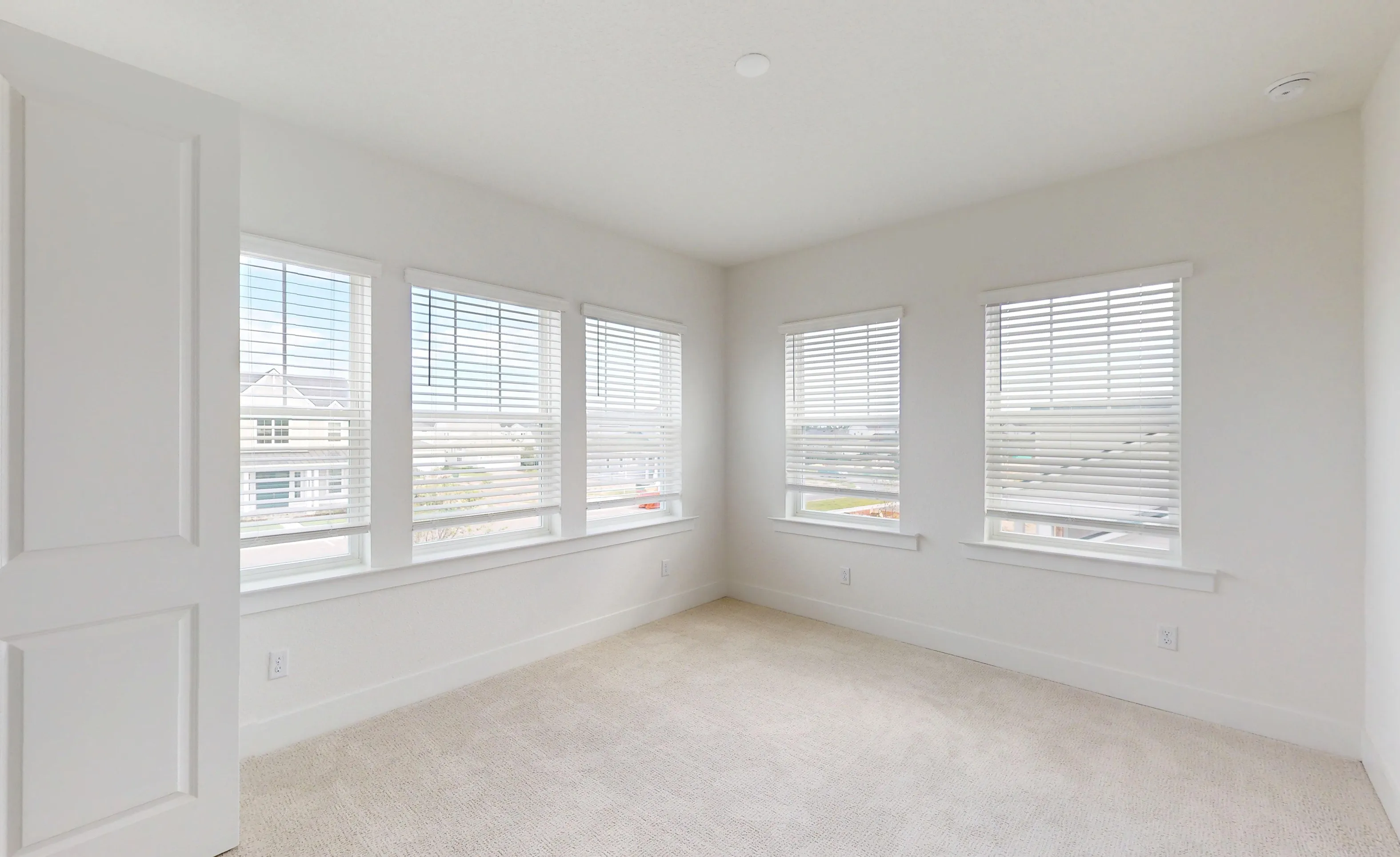 Secondary bedroom with white walls, carpeted floors, and five windows with white horizontal blinds in the Braddock plan.