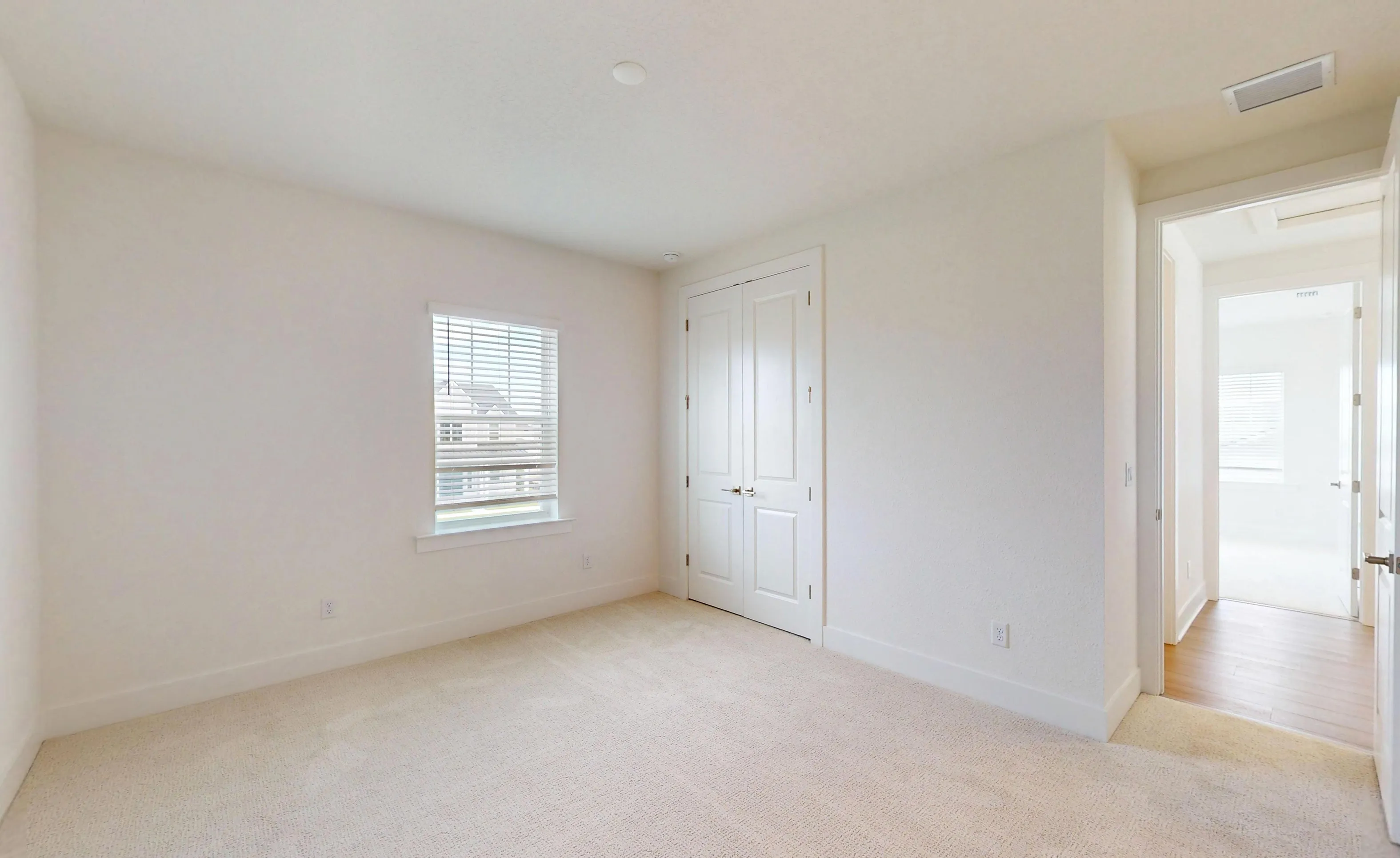 Secondary bedroom in the Braddock plan featuring white walls, beige carpet, a single window with blinds, and double closet.