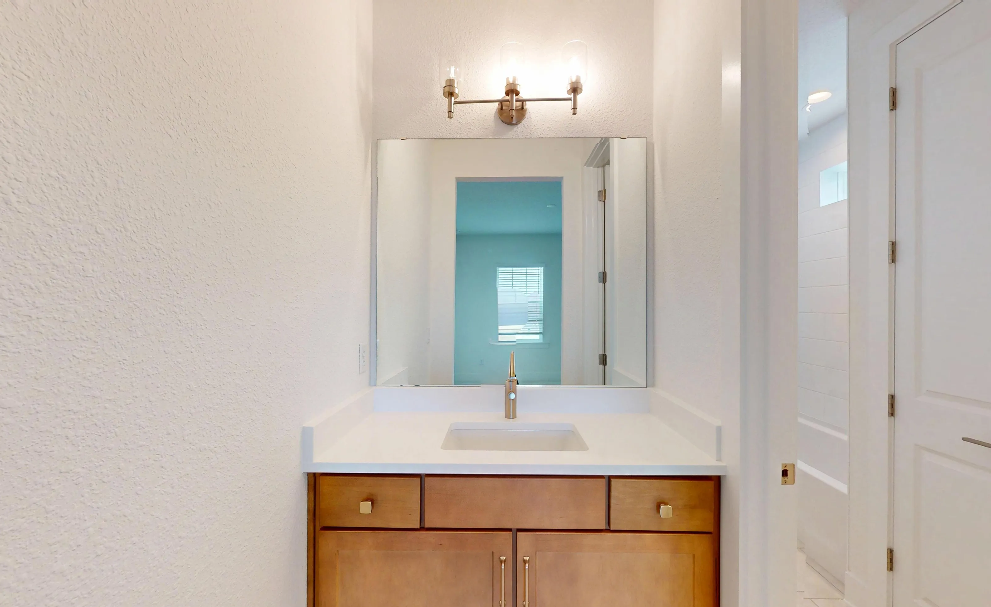 Secondary bath in the Braddock plan with a light wood vanity, white countertop, single sink, and a large wall mirror.