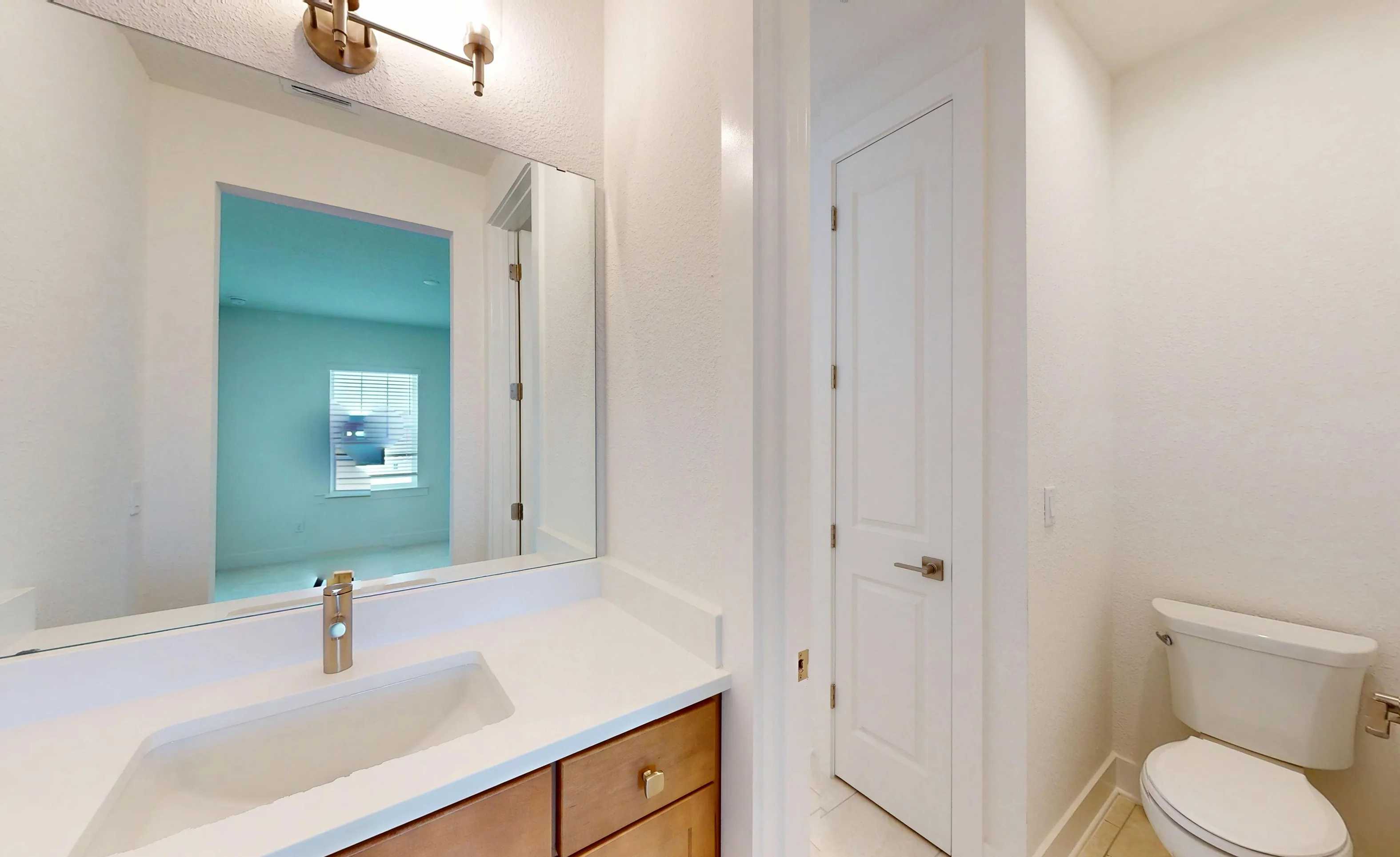Secondary bathroom with a wood vanity, white countertop, modern lighting, a wall mirror, and a white toilet.