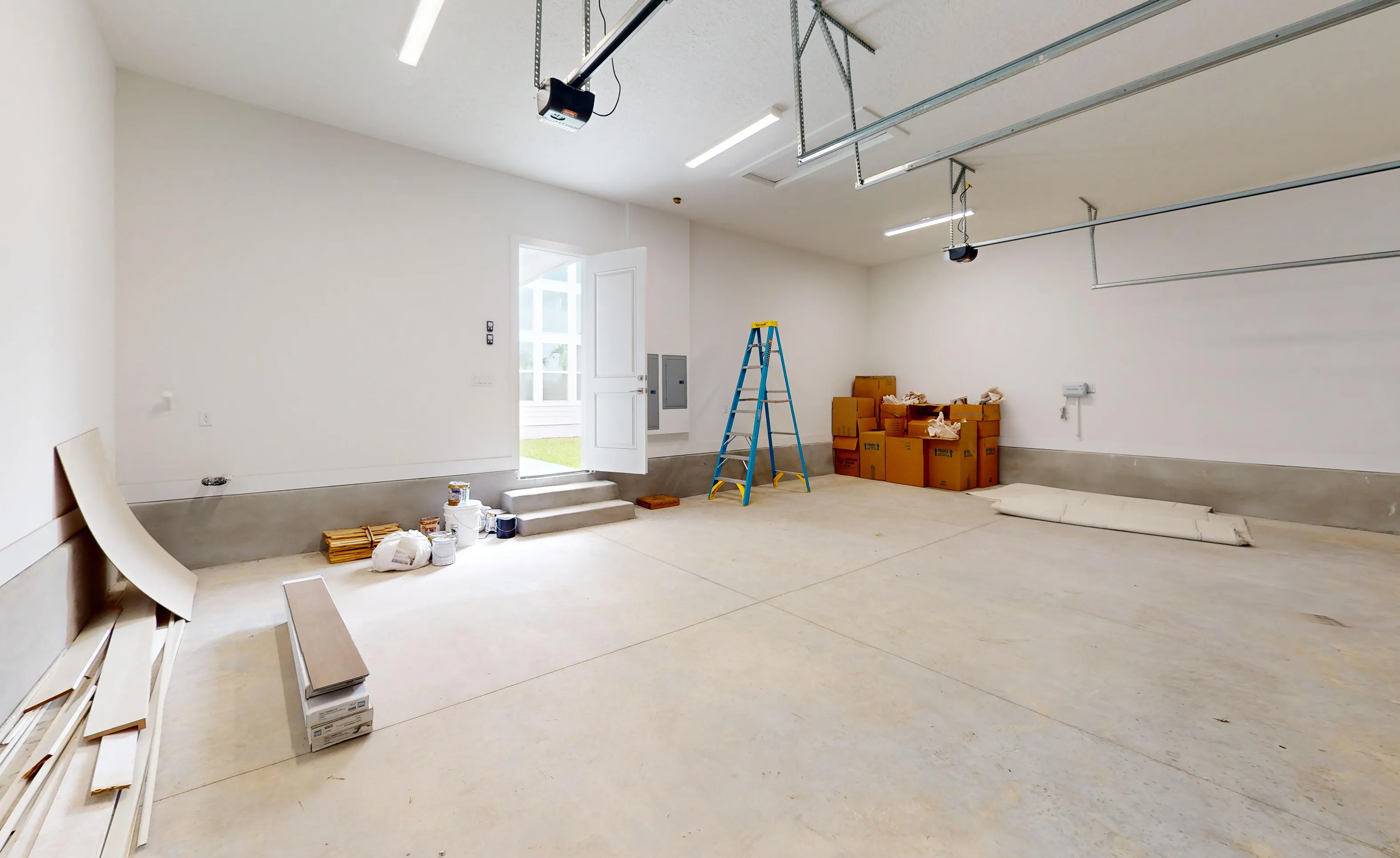 Interior of a spacious, unfinished Braddock plan garage with concrete floors, white walls, and an open side entry door.